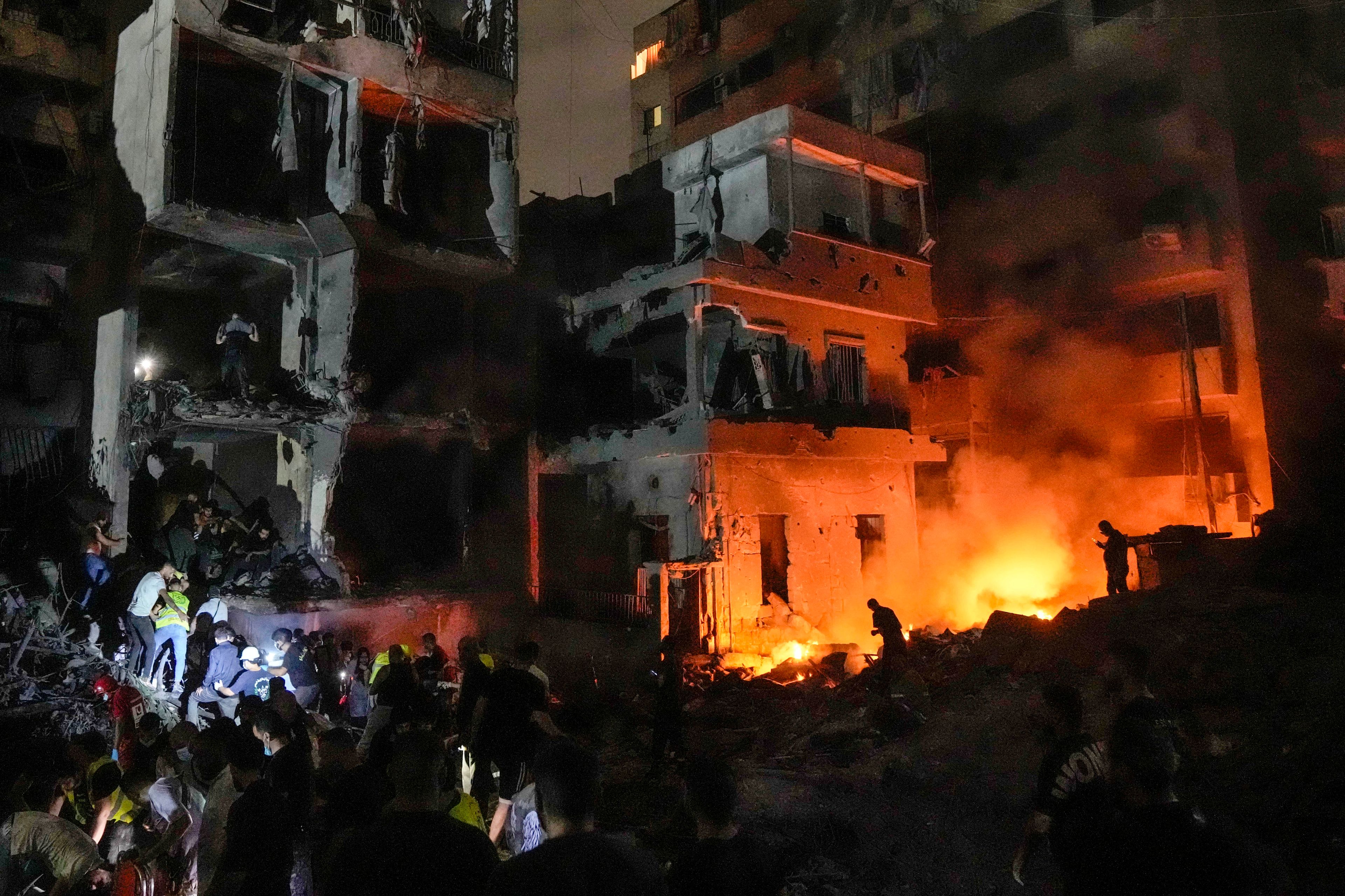 People gather in front of destroyed buildings hit by an Israeli airstrike in central Beirut, Lebanon, Thursday, Oct. 10, 2024. (AP Photo/Bilal Hussein)