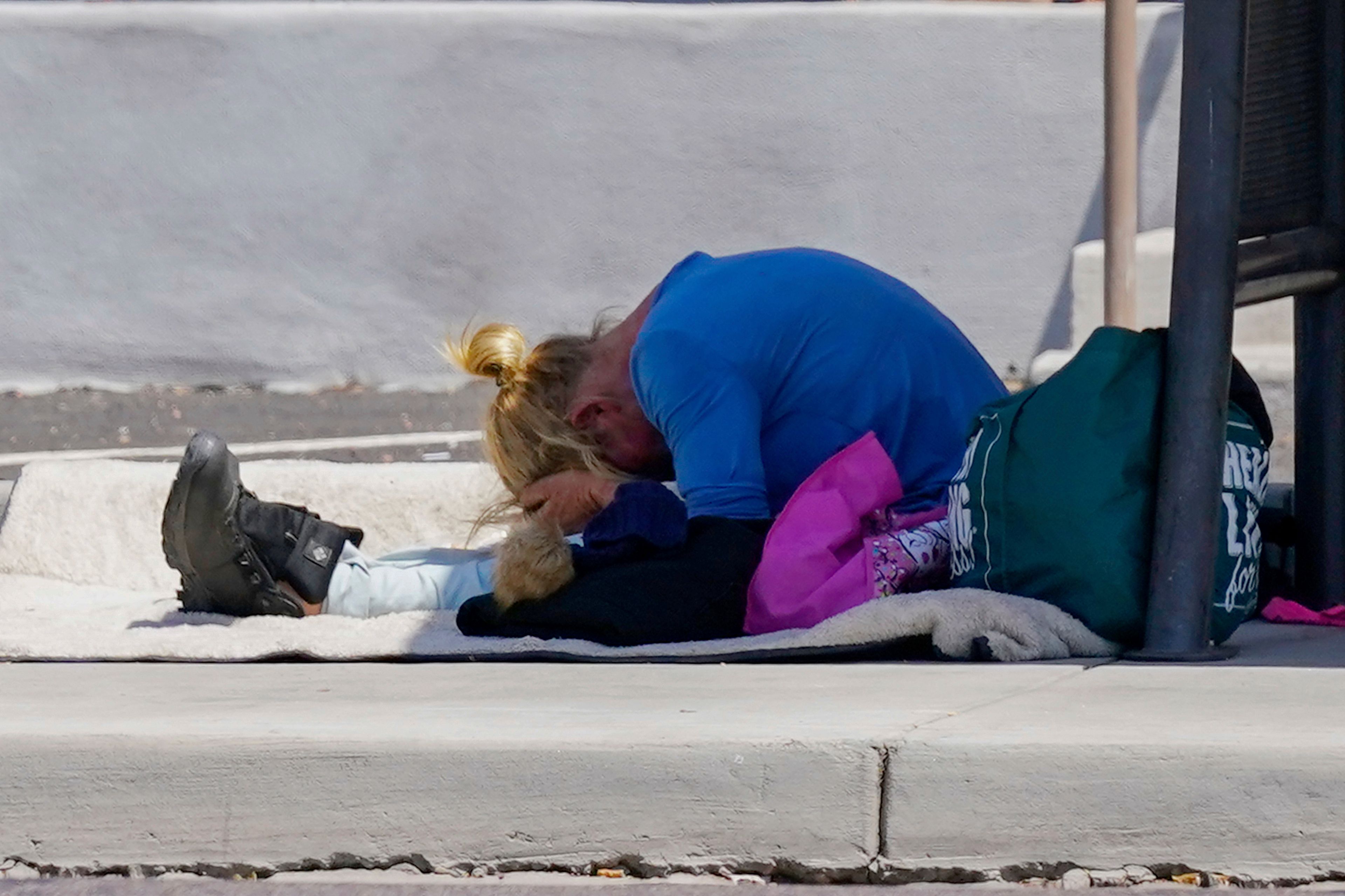 FILE - With hands covering their forehead, a person waits at a bus stop as temperatures are expected to hit 116 degrees on July 18, 2023, in Phoenix. The death certificates of more than 2,300 people who died in the United States last summer mention the effects of excessive heat, the highest number in 45 years of records, according to an Associated Press analysis of Centers for Disease Control and Prevention data. With May already breaking heat records, 2024 could be even deadlier. (AP Photo/Ross D. Franklin, File)