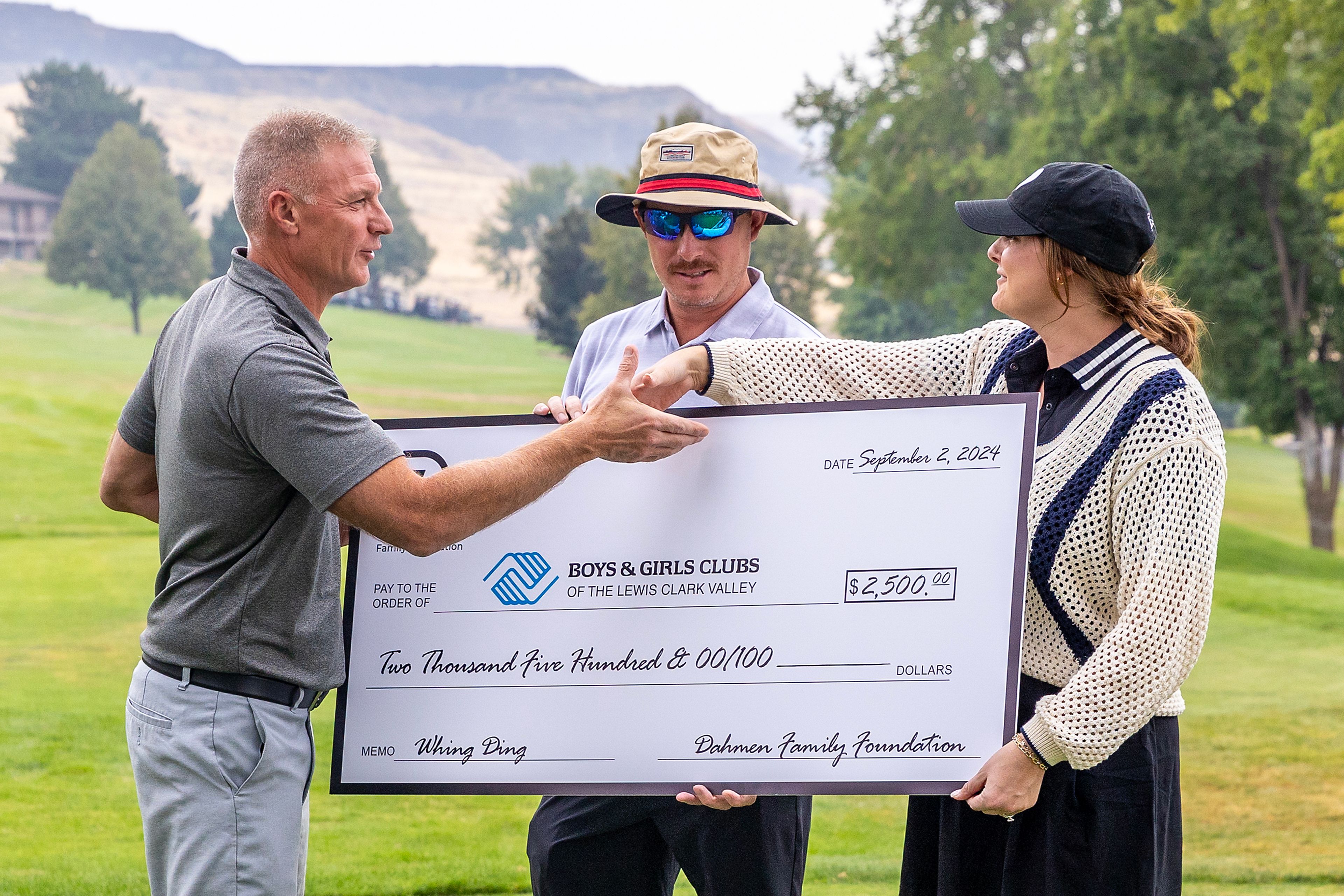 Joel Dahmen (middle) and wife Lona (right) present a check to Tony Mastroberardino of the Boys and Girls Club before the start of the Sole Survivor Tournament Monday at the Lewiston Golf and Country Club.