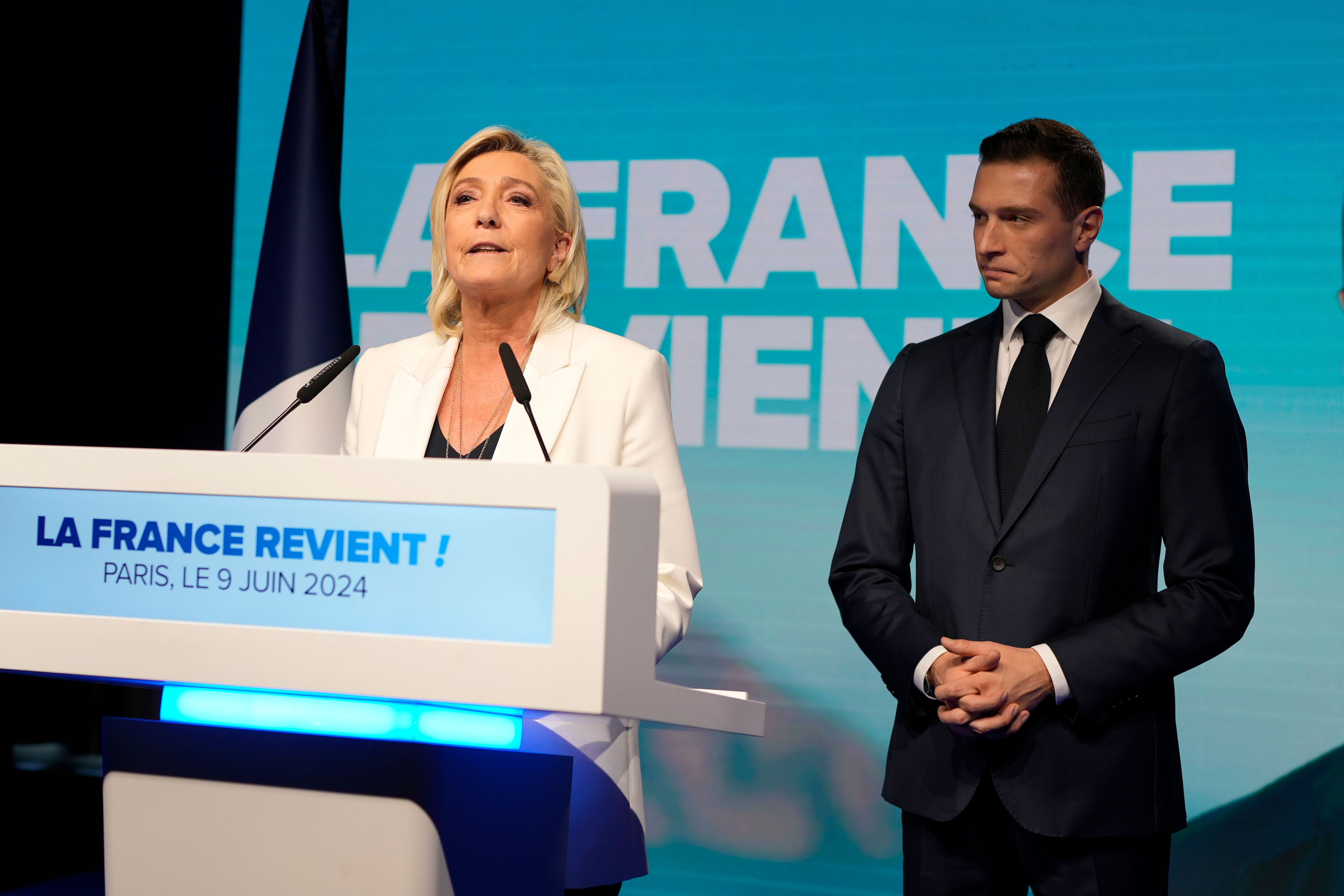 French far-right leader Marine Le Pen speaks as Jordan Bardella, president of the French far-right National Rally, listens at the party election night headquarters after French President Emanuel Macron announced he dissolves National Assembly and calls new legislative election after defeat in EU vote, Sunday, June 9, 2024 in Paris. First projected results from France put far-right National Rally party well ahead in EU elections, according to French opinion poll institutes.