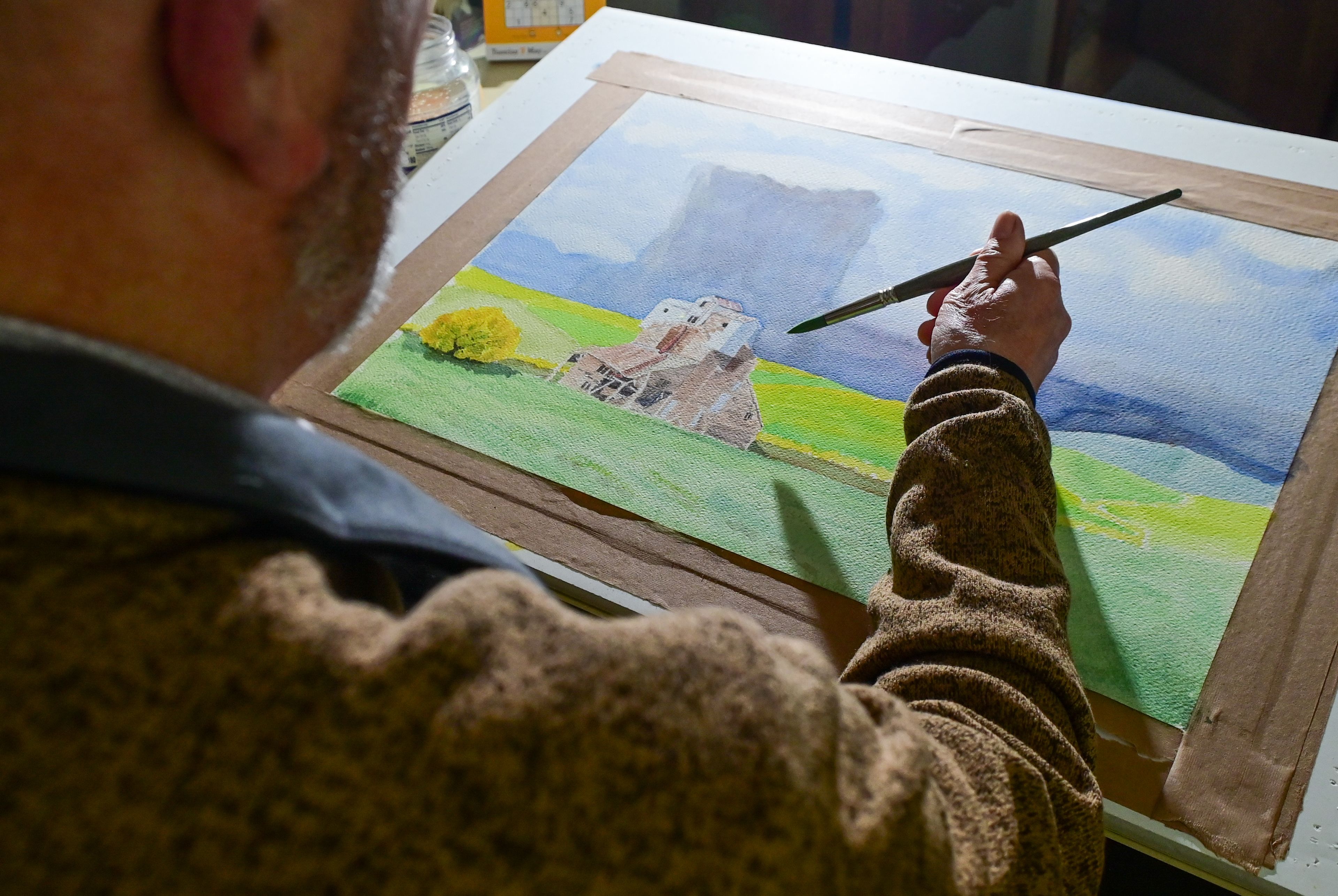 Ernie Weiss, president of the Palouse Watercolor Socius, holds a brush above an in-progress watercolor piece, named “Abandoned,” that will be entered in the 50th anniversary show for the group.