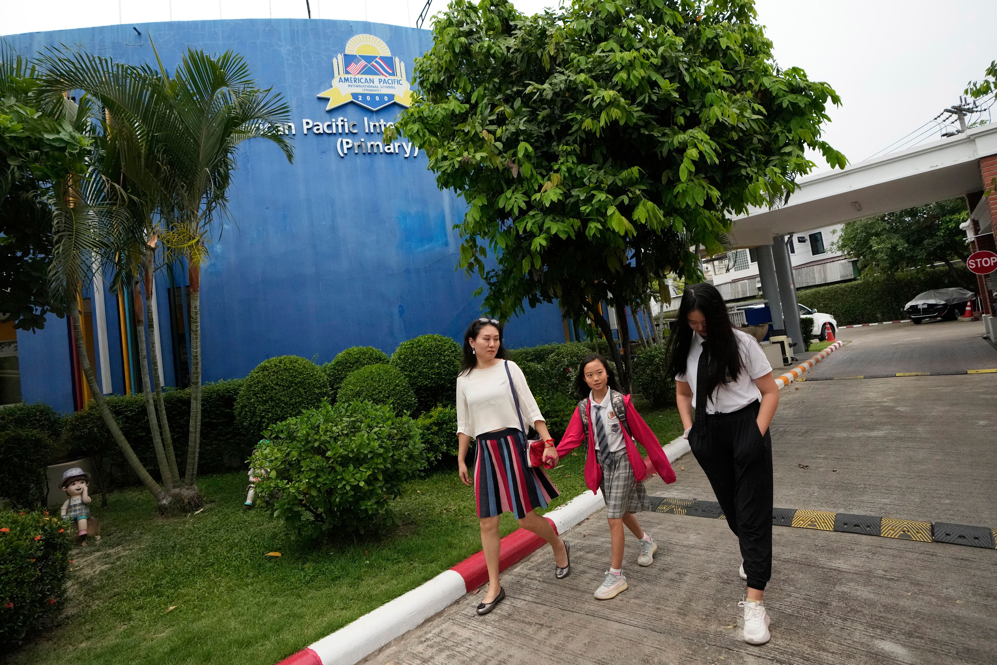 Chinese mother Du Xuan, left, picks up her daughters May Yu, center, and Annie Yu from school in Chiang Mai province, Thailand, Tuesday, April 23, 2024.