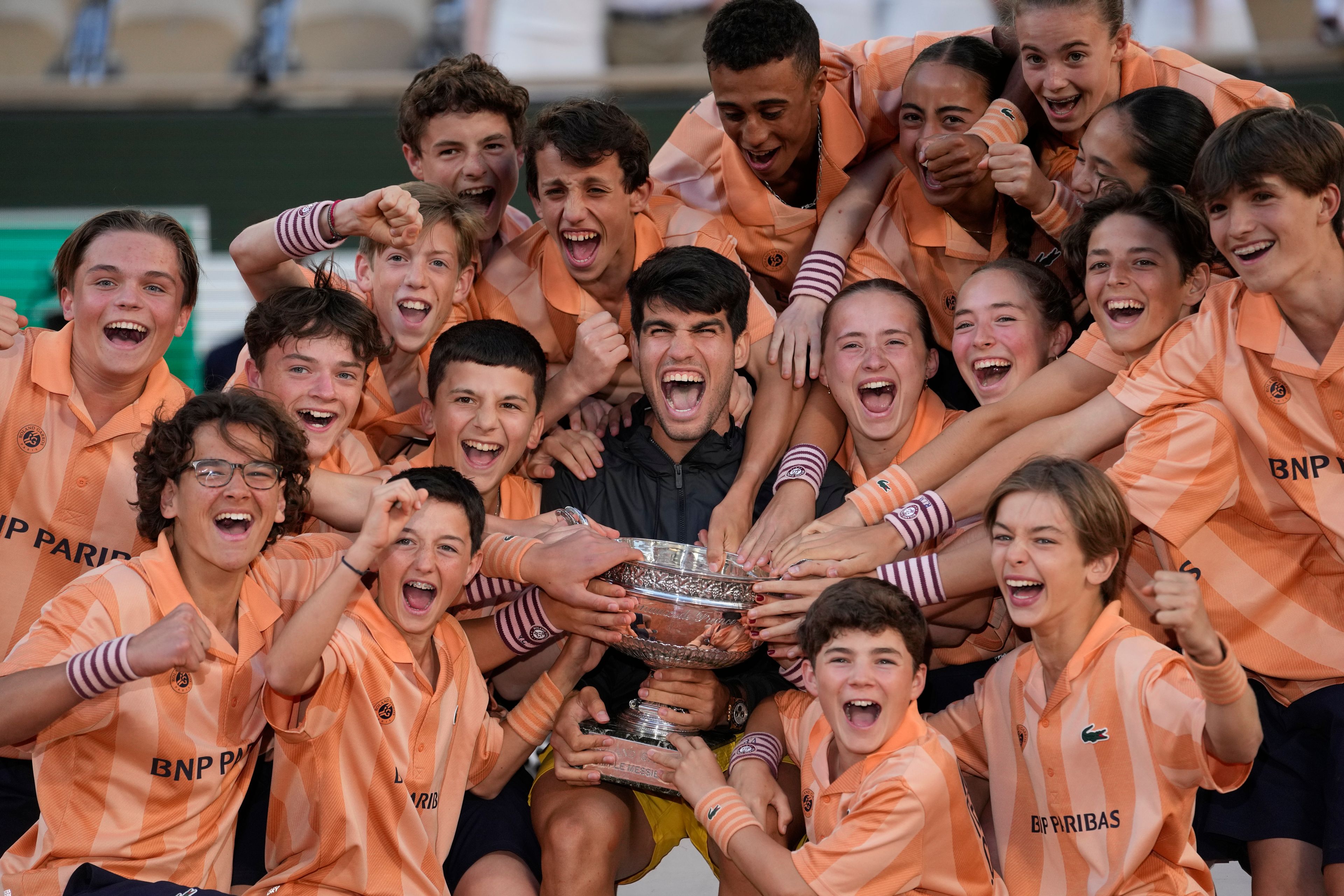 Winner Spain's Carlos Alcaraz poses for a picture with poses with ball girls and boys after the men's final match of the French Open tennis tournament against Germany's Alexander Zverev at the Roland Garros stadium in Paris, Sunday, June 9, 2024.