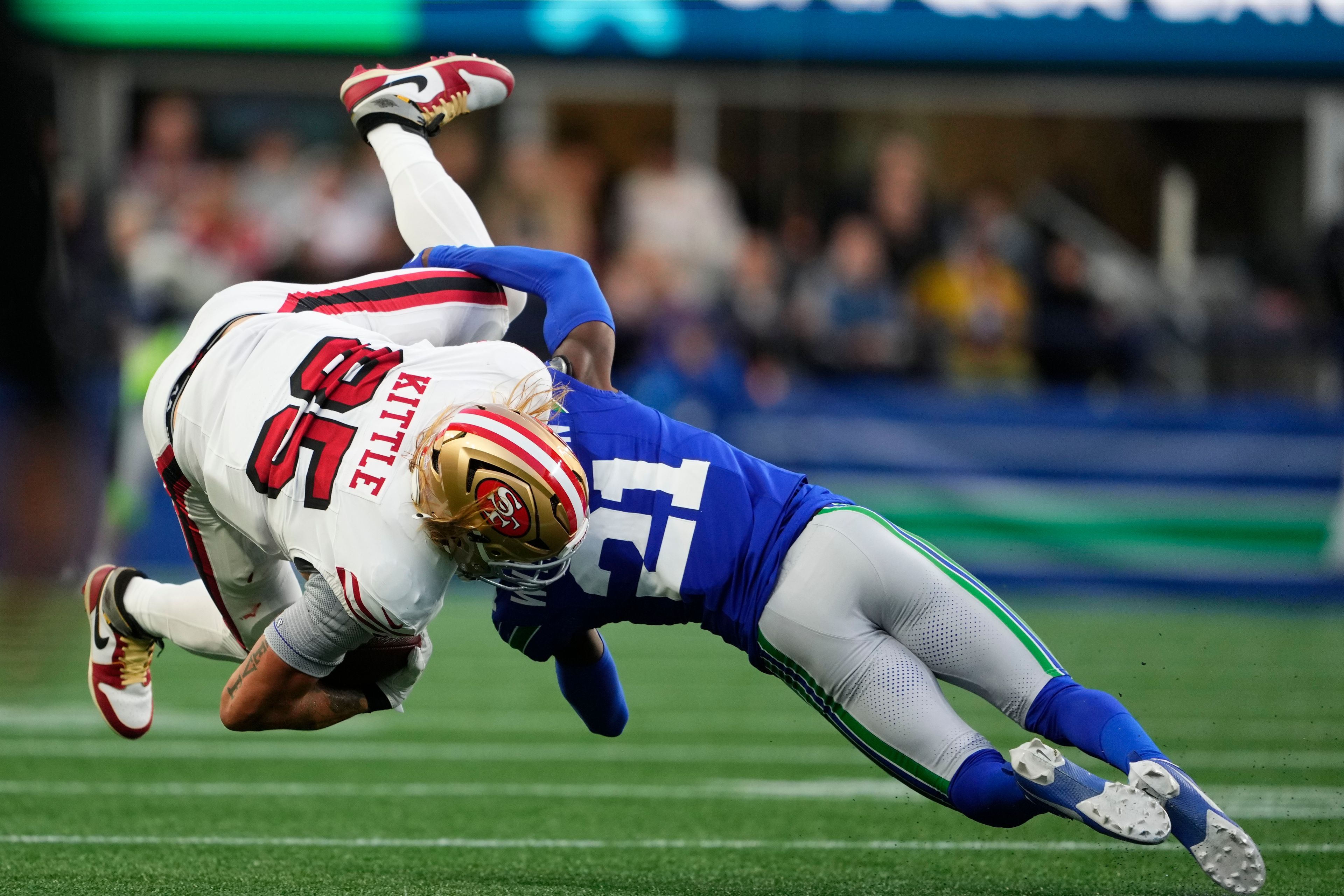 San Francisco 49ers' George Kittle (85) os tacked by Seattle Seahawks' Devon Witherspoon (21) during the first half of an NFL football game, Thursday, Oct. 10, 2024, in Seattle. (AP Photo/Lindsey Wasson)