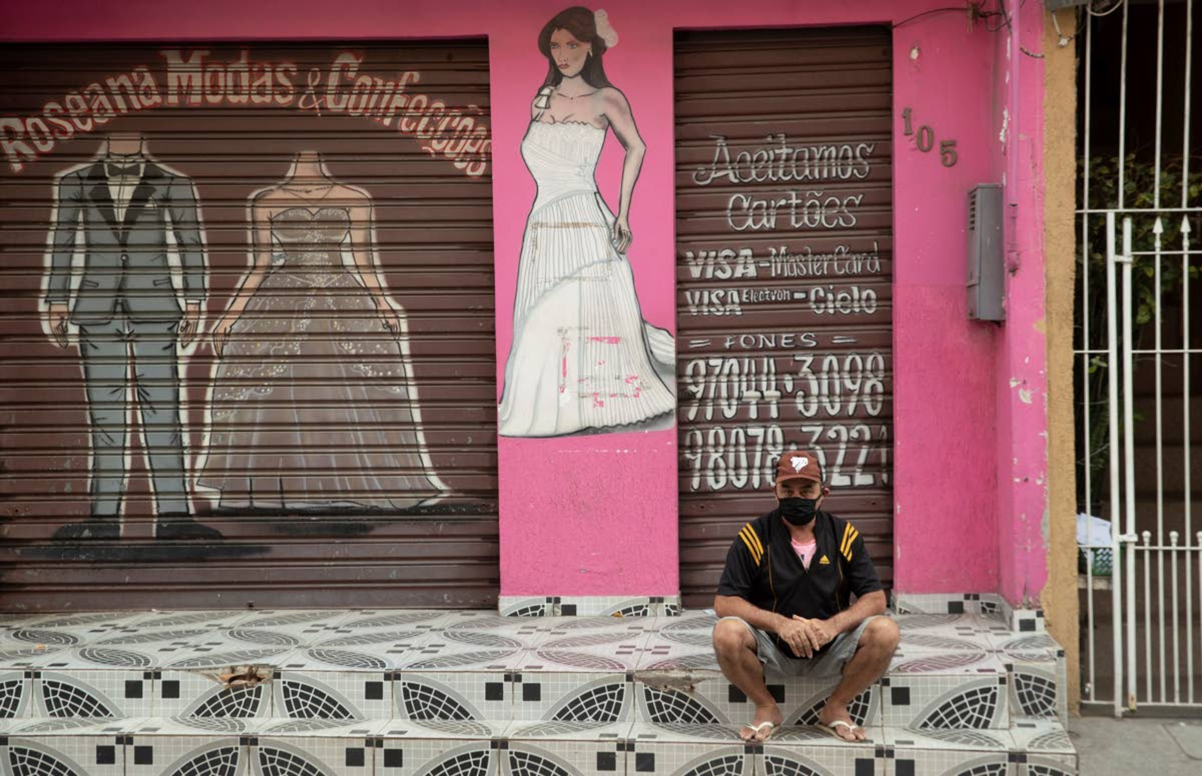 A man sits outside a shuttered store, closed due to the lockdown aimed at curbing the spread of the new coronavirus in the Paraisopolis slum of Sao Paulo, Brazil, Wednesday, May 6, 2020. With over 100,000 residents, Paraisopolis is one of the areas most affected by COVID-19 in Sao Paulo. (AP Photo/Andre Penner)