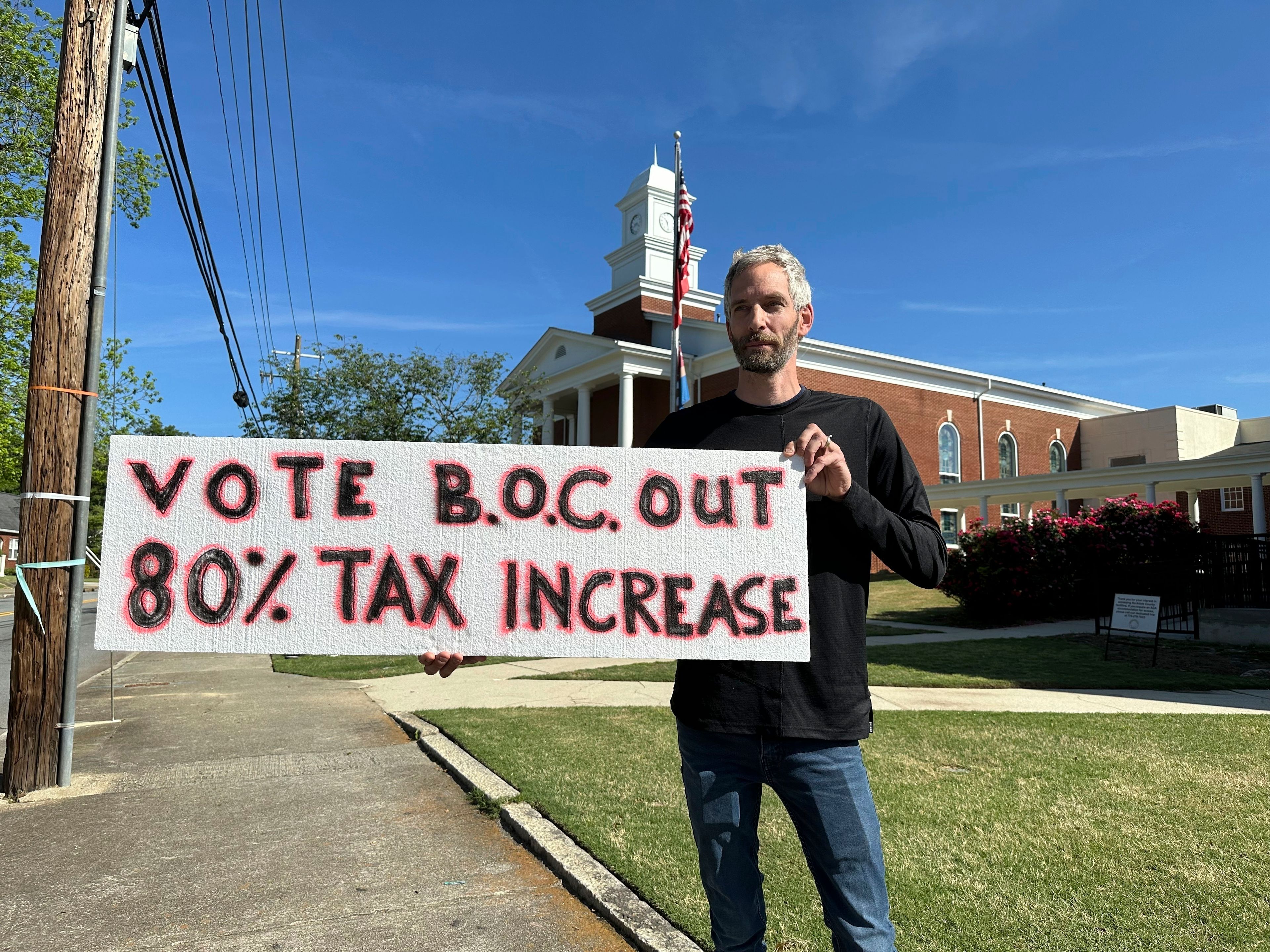 Rob Romeijn protests property taxes outside Rockdale County offices in Conyers, Ga., on April 23, 2024. Romeijn says the increase in the taxable value of his house is unfair, but future increases in taxable values could be curbed if Georgia voters approve a referendum in November.