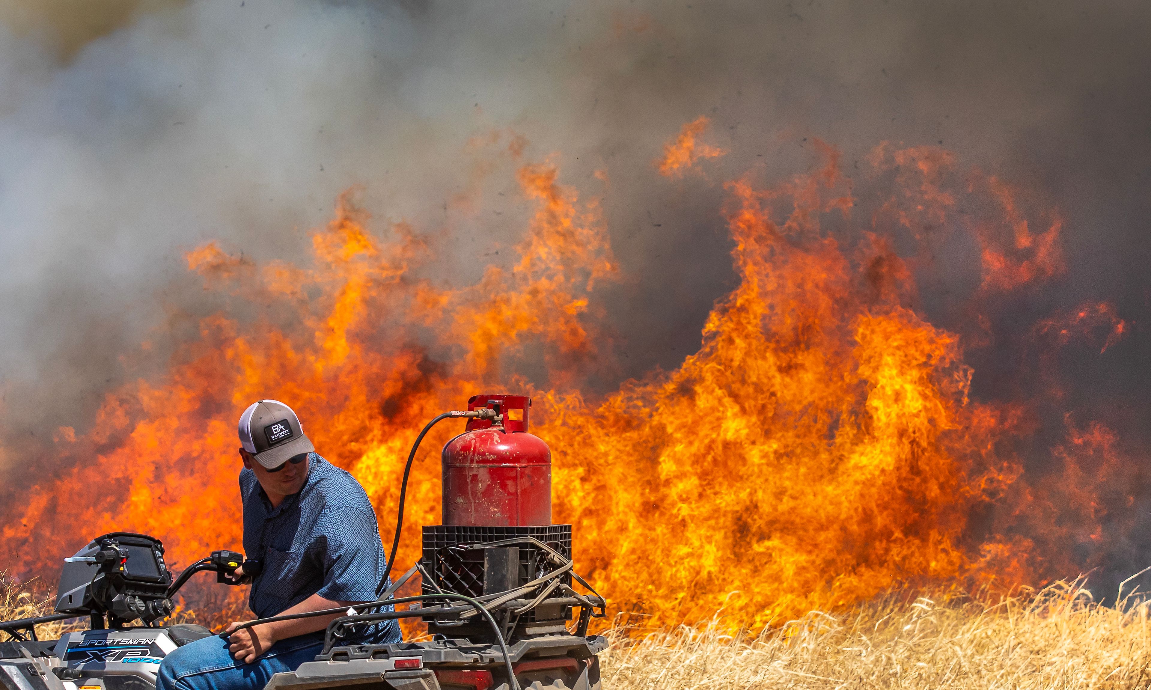 A worker looks back at the line of fire he is starting for a controlled burn Friday in a field south of Lewiston.