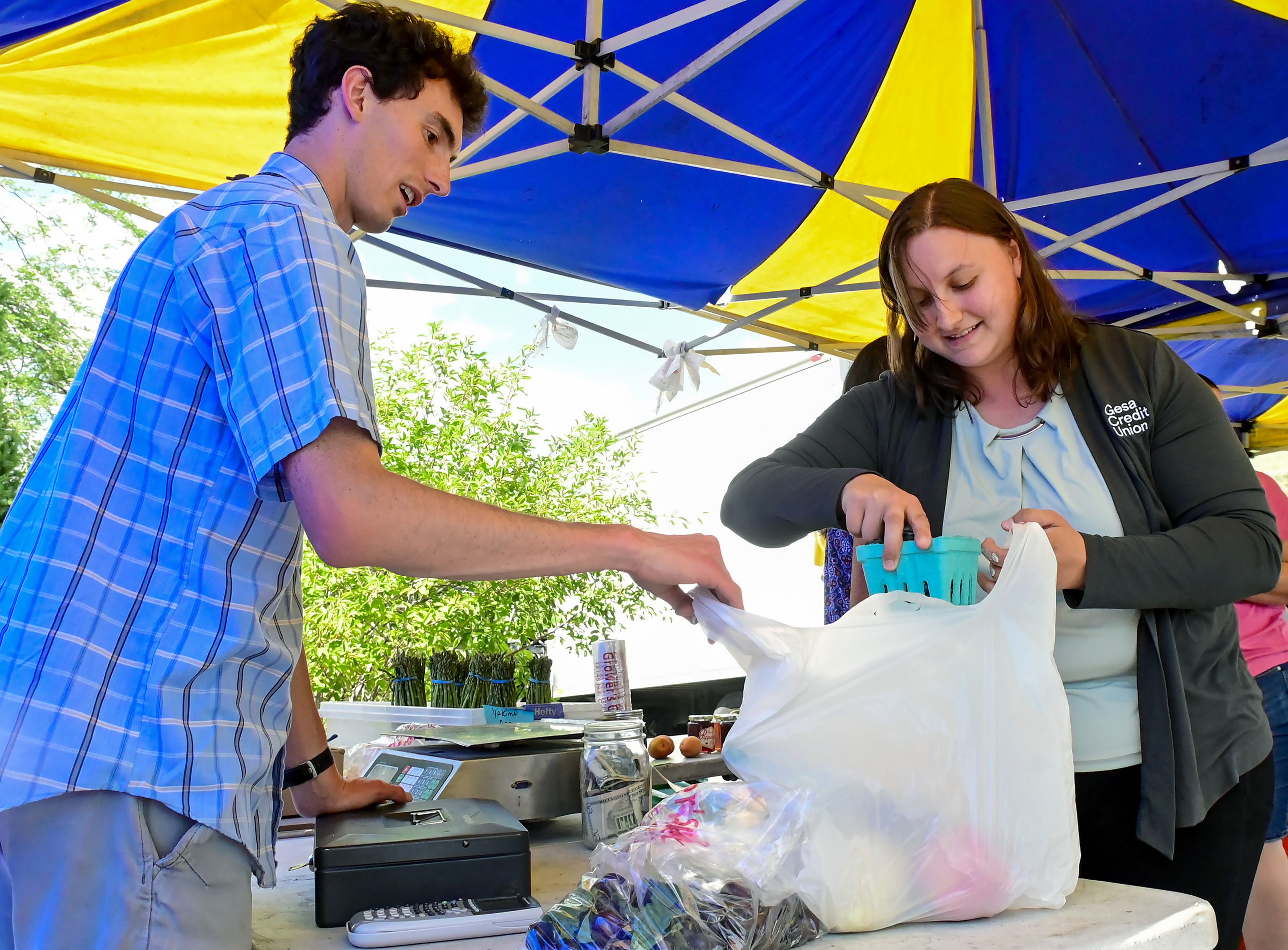 Joshua Johnson helps Jacqui Thomasson, of Pullman, bag up her fruit finds at the Sweet Melon Shack on Wednesday in Pullman. The fruit stand recently moved down the street from its previous location to the Real Life Church parking lot along Grand Avenue.