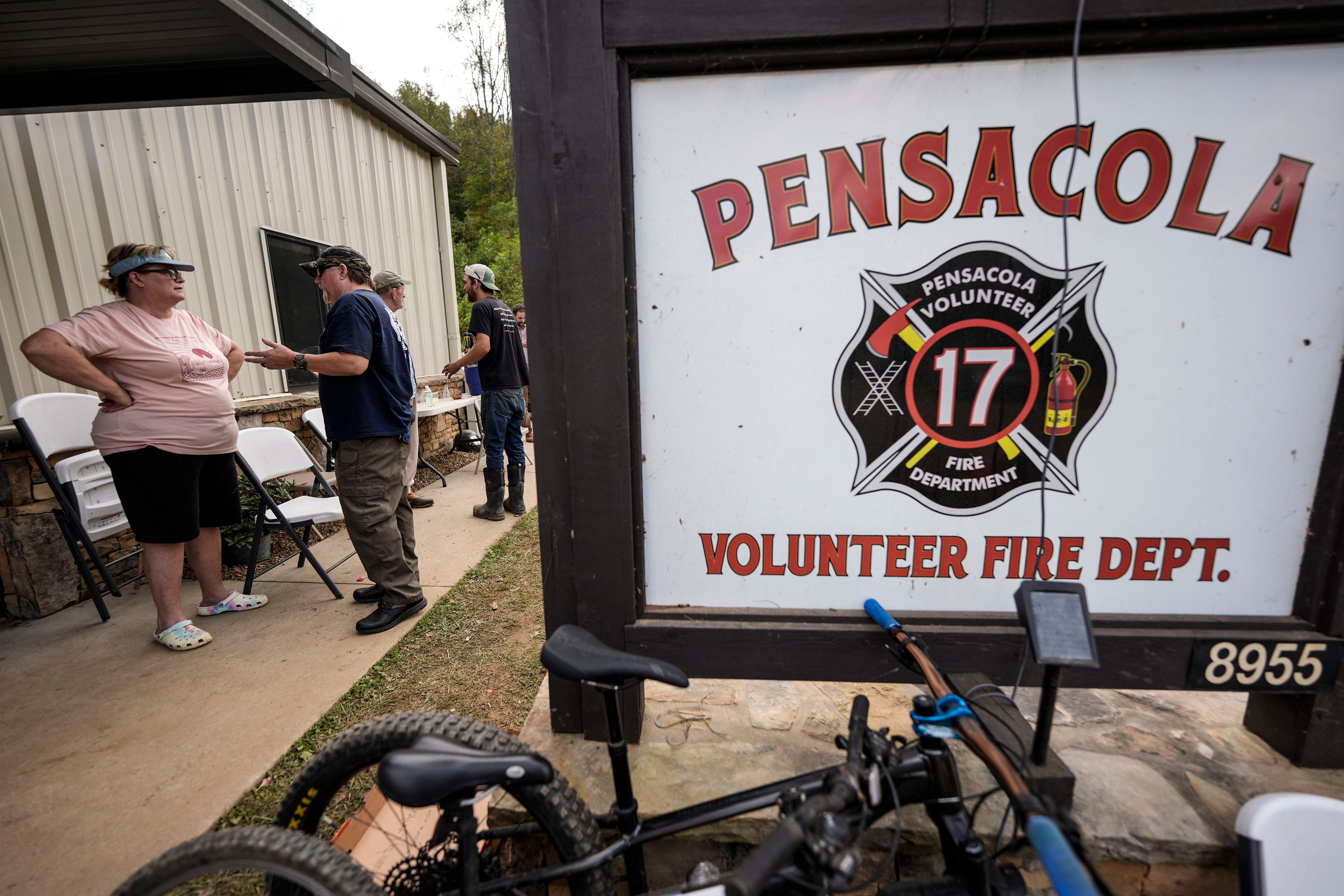 People speak outside the volunteer fire house in the aftermath of Hurricane Helene, Thursday, Oct. 3, 2024, in Pensacola, N.C. (AP Photo/Mike Stewart)