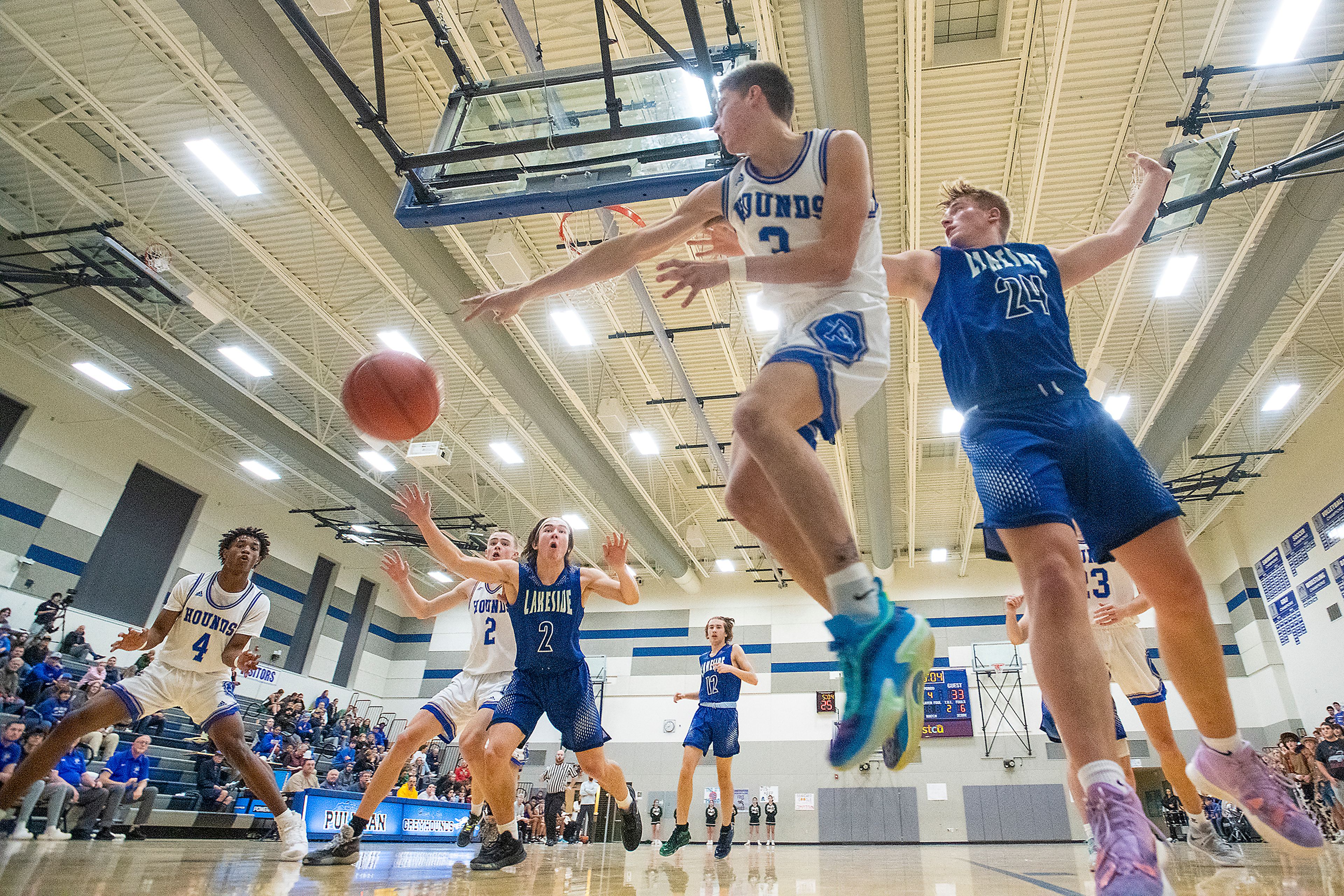 Pullman guard Tanner Barbour, center, leaps above the baseline to pass the ball to teammate Champ Powaukee, left, during Friday’s nonleague game against Lakeside.