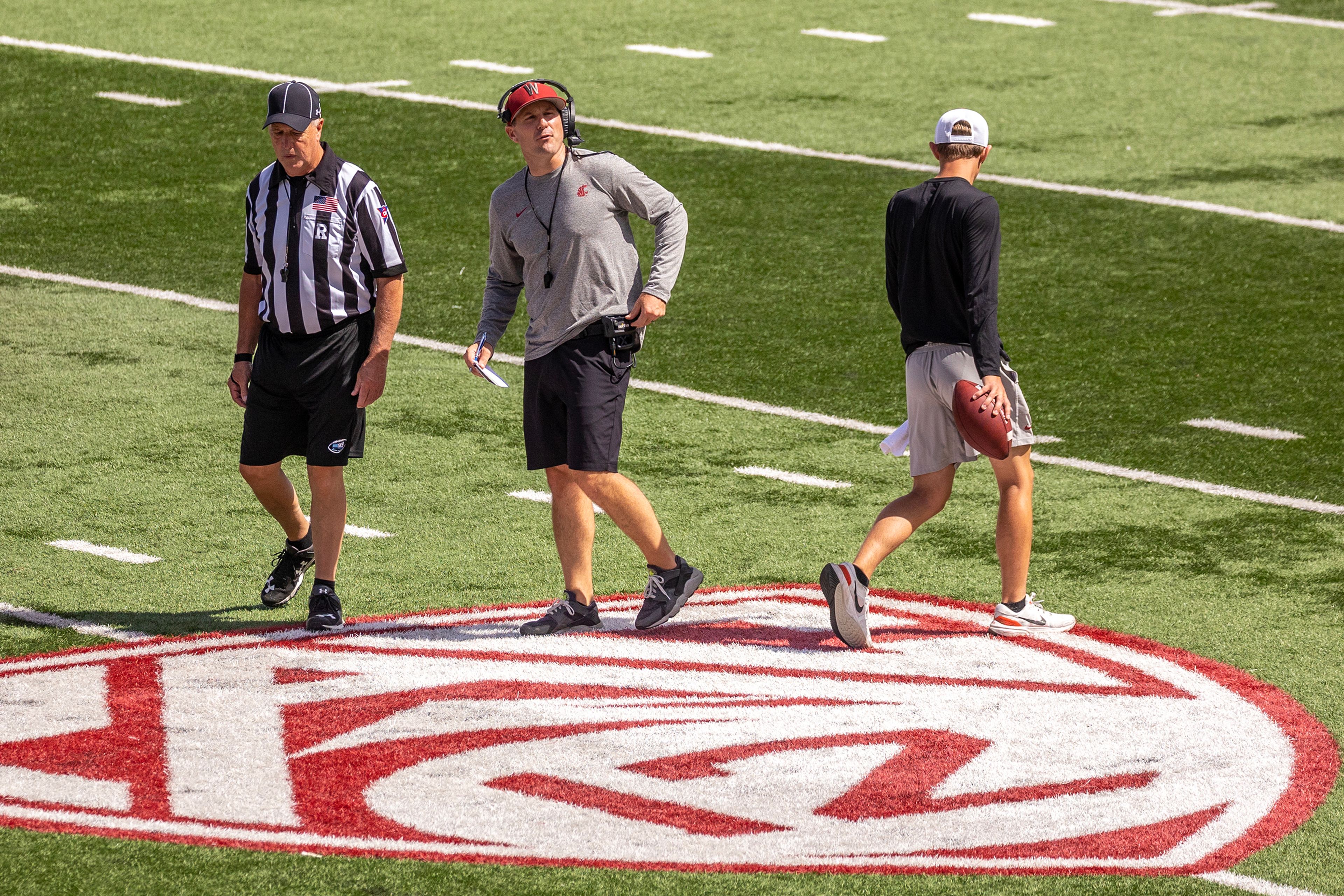 Head Coach Jake Dickert walks across the Pac-12 logo on the field during a scrimmage at Martin Stadium Saturday in Pullman.