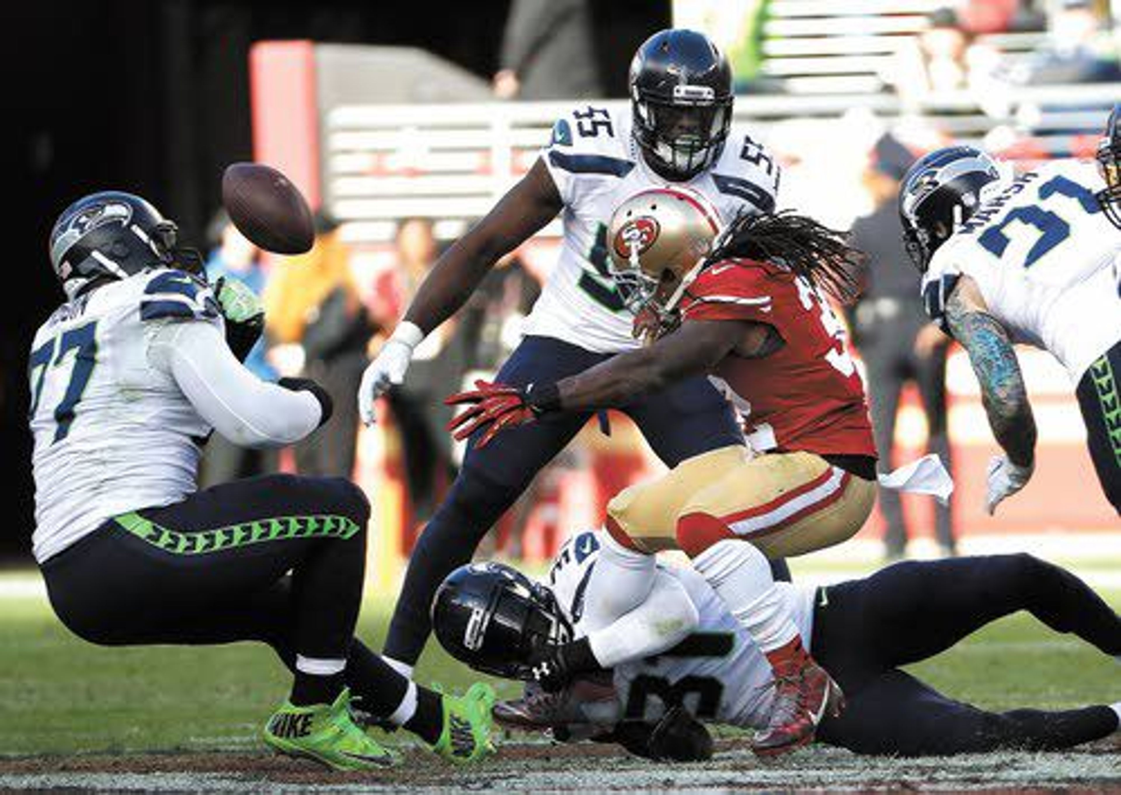 Ahtyba Rubin (left) of the Seahawks watches the ball pop loose from San Francisco running back DuJuan Harris in front of Frank Clark (55). Seattle beat the Niners 25-23 on Sunday at Santa Clara, Calif.