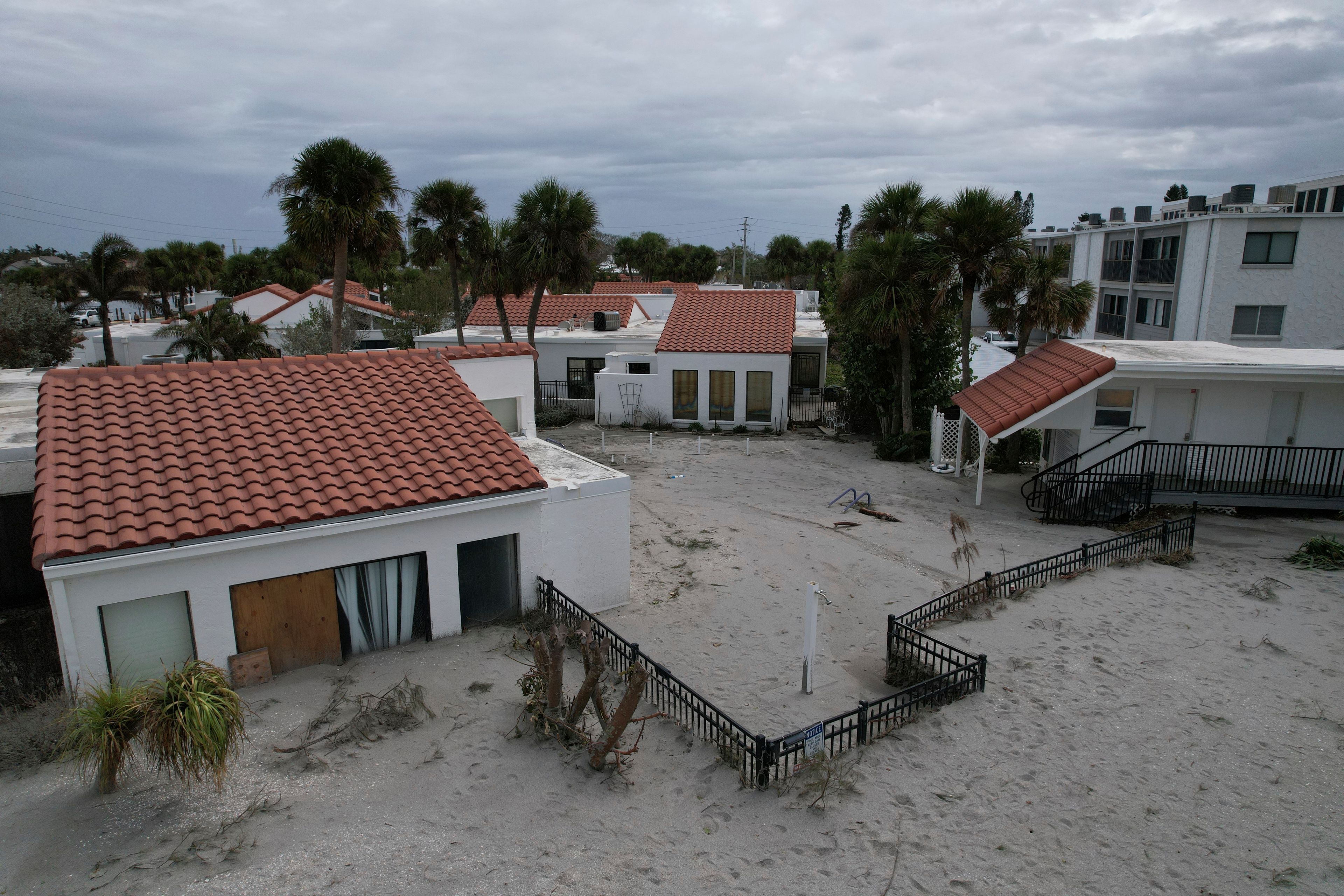 Sand swept by Hurricane Milton reaches half-way up the sliding doors of a beachfront villa, next to a pool deck where the 8 1/2 foot deep pool had disappeared under sand, at Jetty Villas on the island of Venice, Fla., Friday, Oct. 11, 2024. (AP Photo/Rebecca Blackwell)