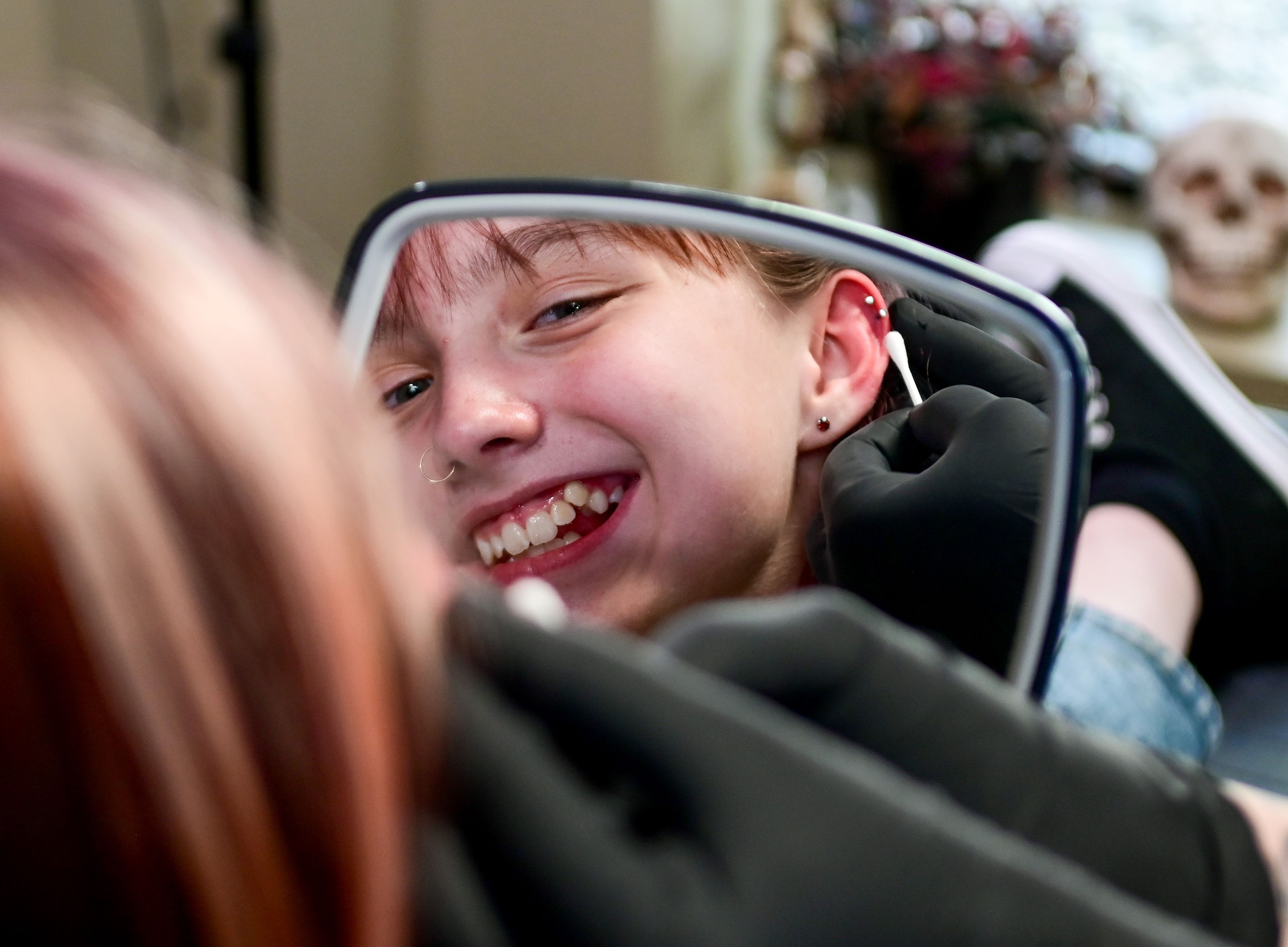 Lillian Szumlas, 13, of Pullman, looks at her two new cartilage piercings in a hand mirror at the new piercing studio Wednesday, April 17, at Blood Diamond Ink in Pullman.