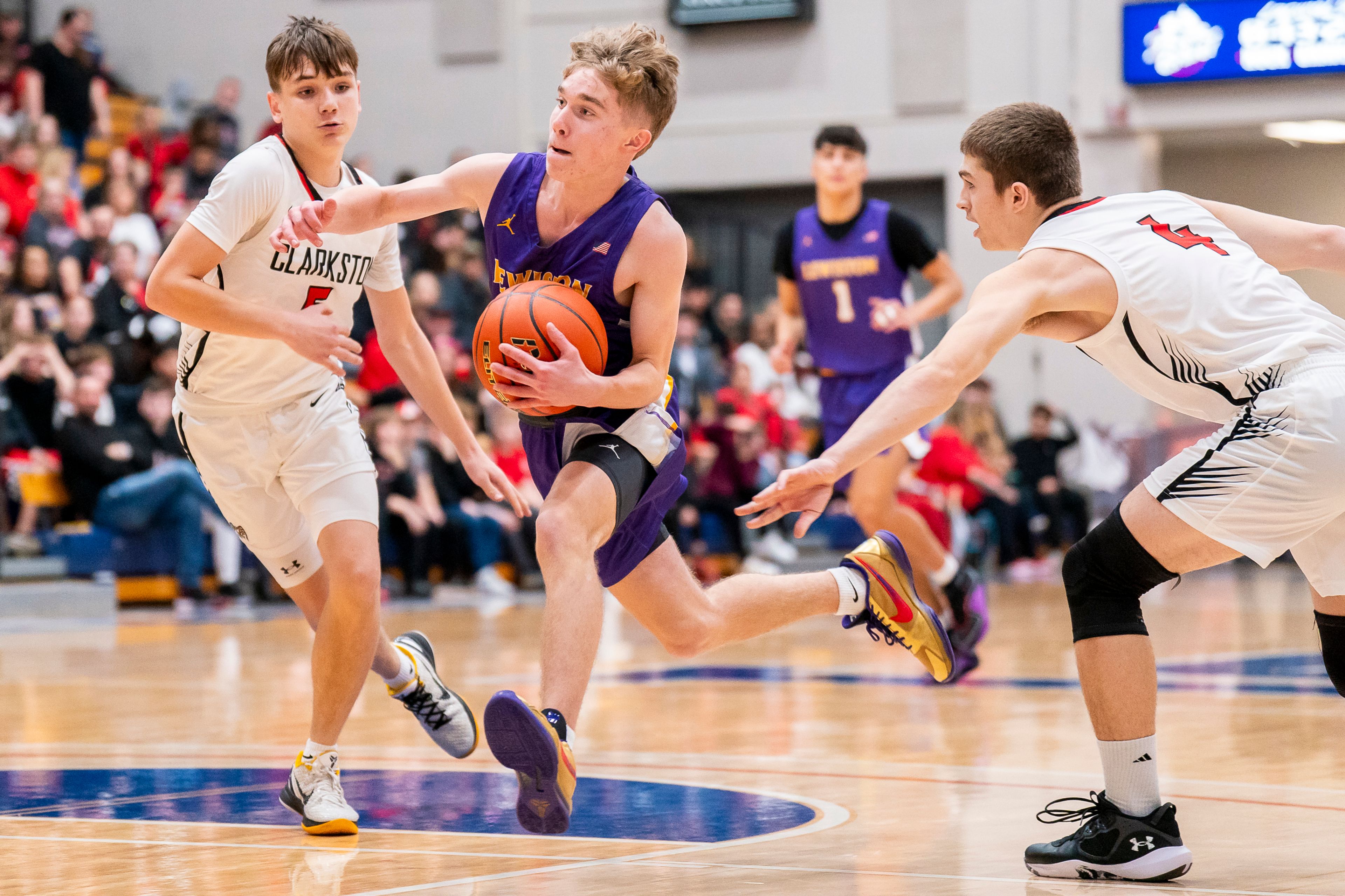 Lewiston’s Jordan Walker, center, drives to the basket during their Golden Throne rivalry game against Clarkston on Friday inside the P1FCU Activity Center in Lewiston.