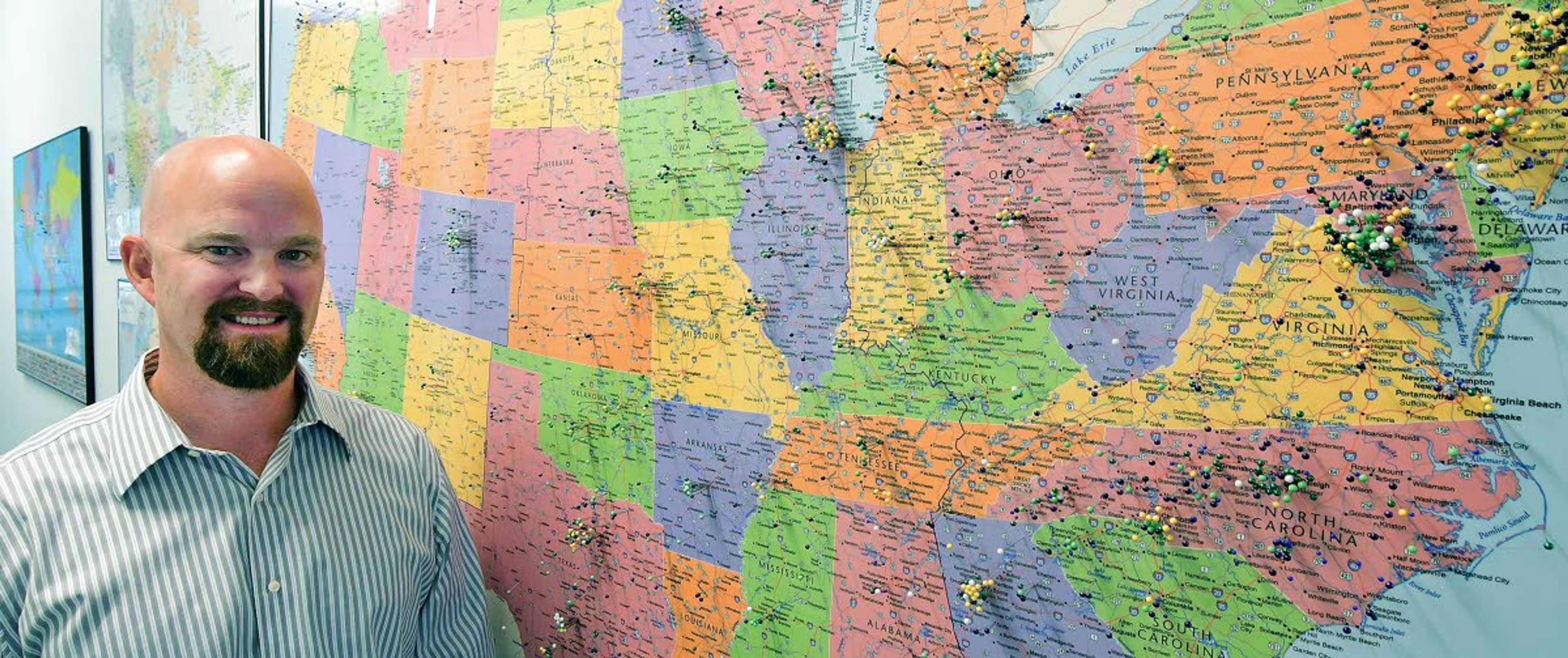 Andrew Crapuchettes, Emsi CEO, poses by a map of the United States that shows the locations of his firm’s many customers.