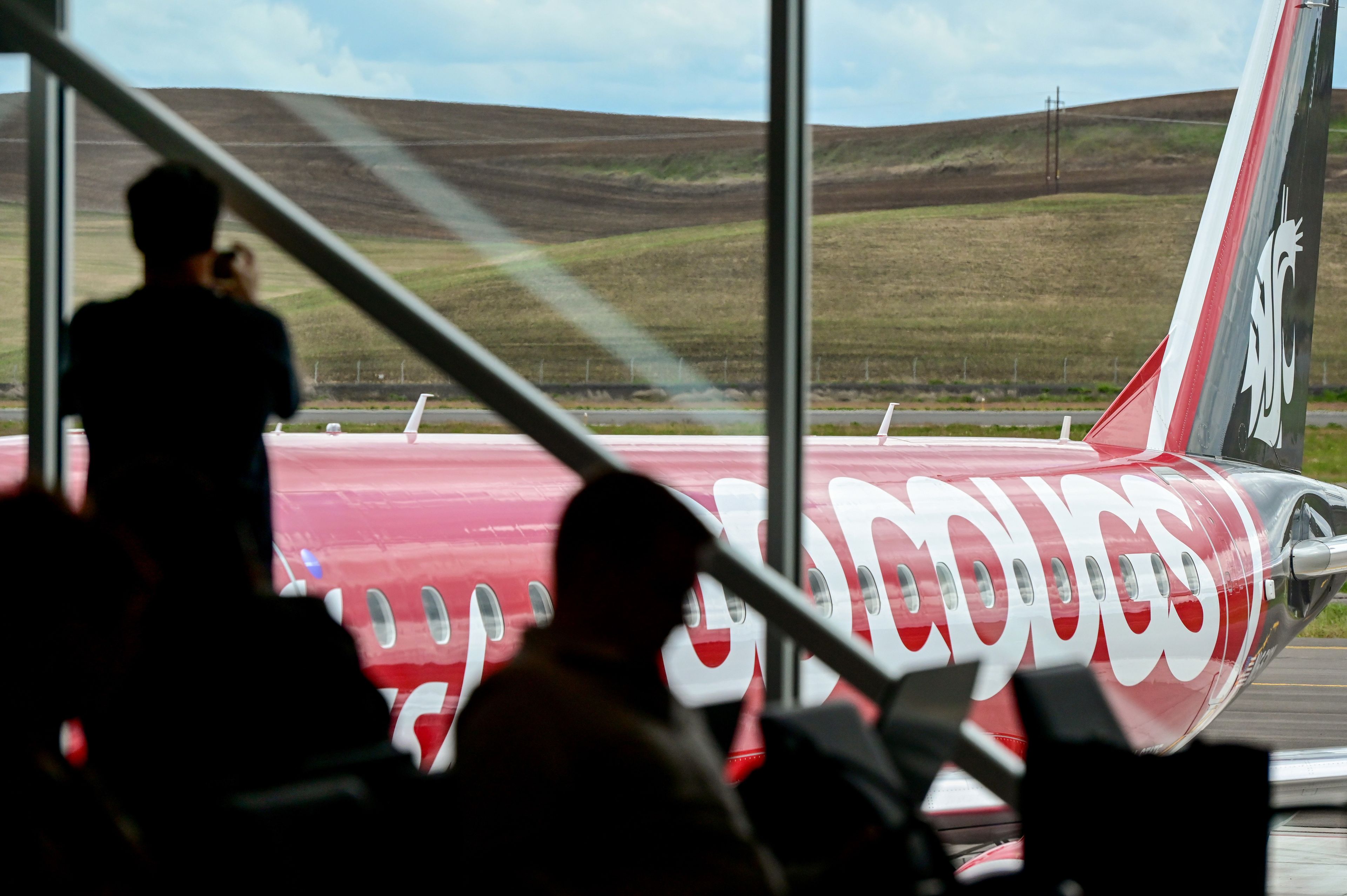 A passenger takes a photo of the “Go Cougs” jet pulled up in front of a gate of the new Pullman-Moscow Regional Airport terminal for its first day of flights in Pullman on Wednesday.