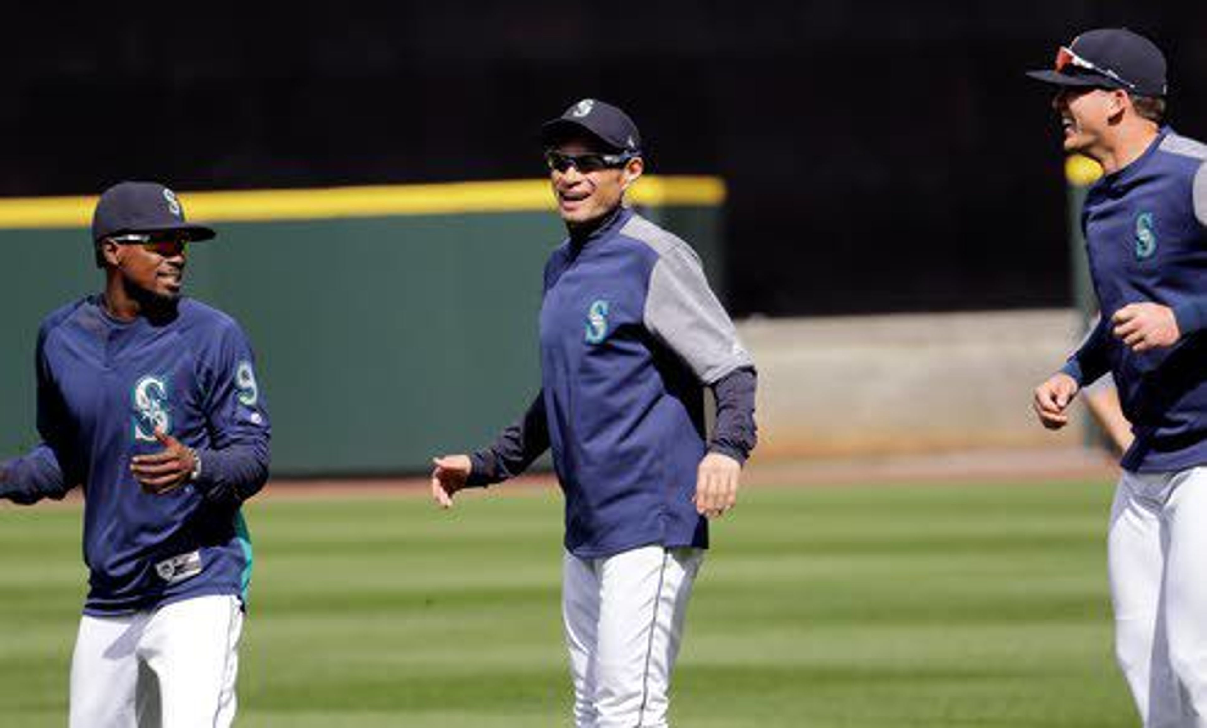 Seattle Mariners' Ichiro Suzuki, center, smiles as he jogs with Dee Gordon, left, and Ryon Healy during a practice on the baseball team's home field Wednesday, March 28, 2018, in Seattle. The team opens play Thursday against the Cleveland Indians. (AP Photo/Elaine Thompson)