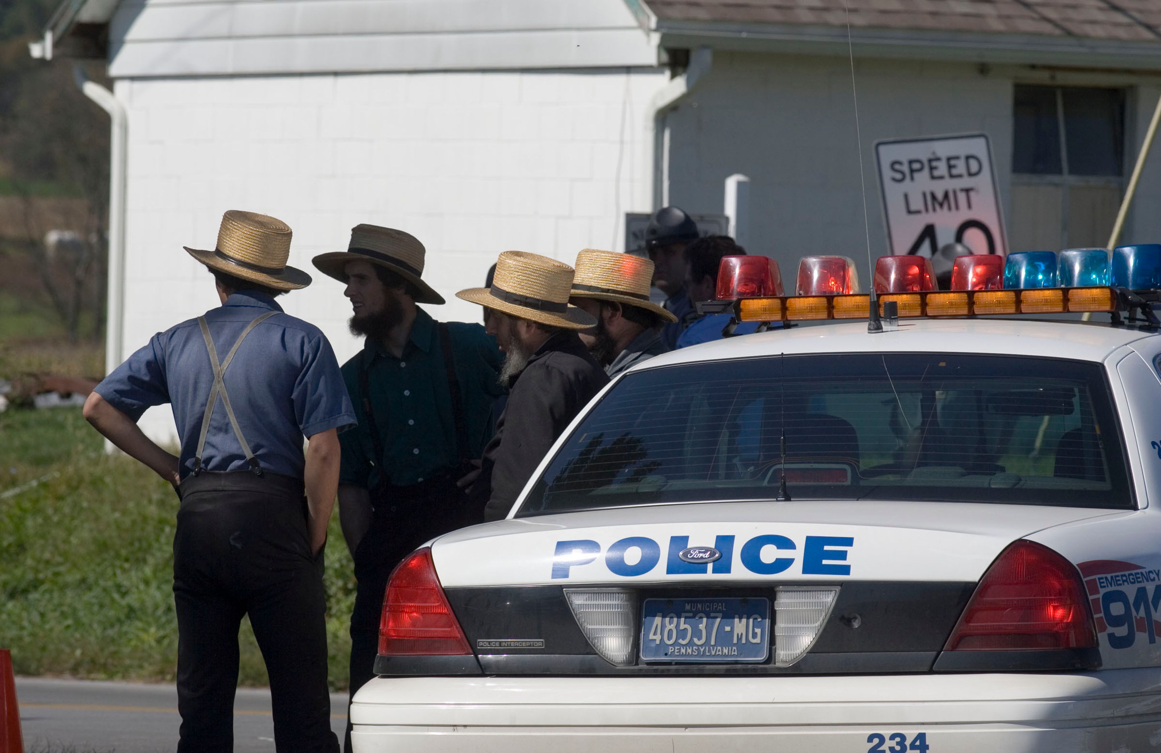 FILE - A group of Amish men wait at a roadblock near the West Nickel Mines Amish School, in which a gunman killed several people and injured others, in Nickel Mines, Pa., on Oct. 2, 2006.