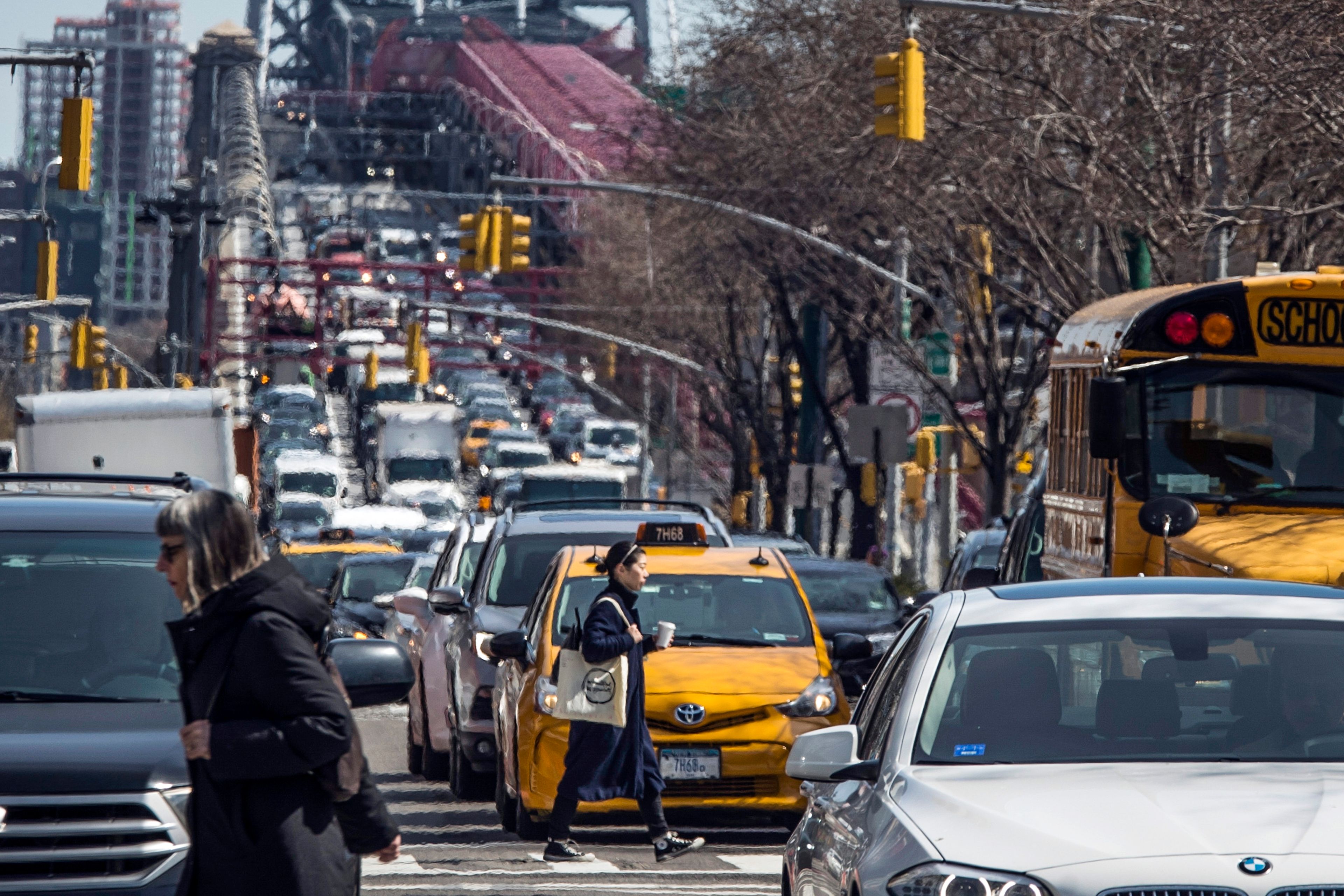 FILE - Pedestrians cross Delancey Street as congested traffic from Brooklyn enters Manhattan over the Williamsburg Bridge, March 28, 2019, in New York. New York Gov. Kathy Hochul is trying to raise taxes on businesses in the city to close a big budget gap that emerged after she halted a plan to charge drivers a toll to enter the center of Manhattan.