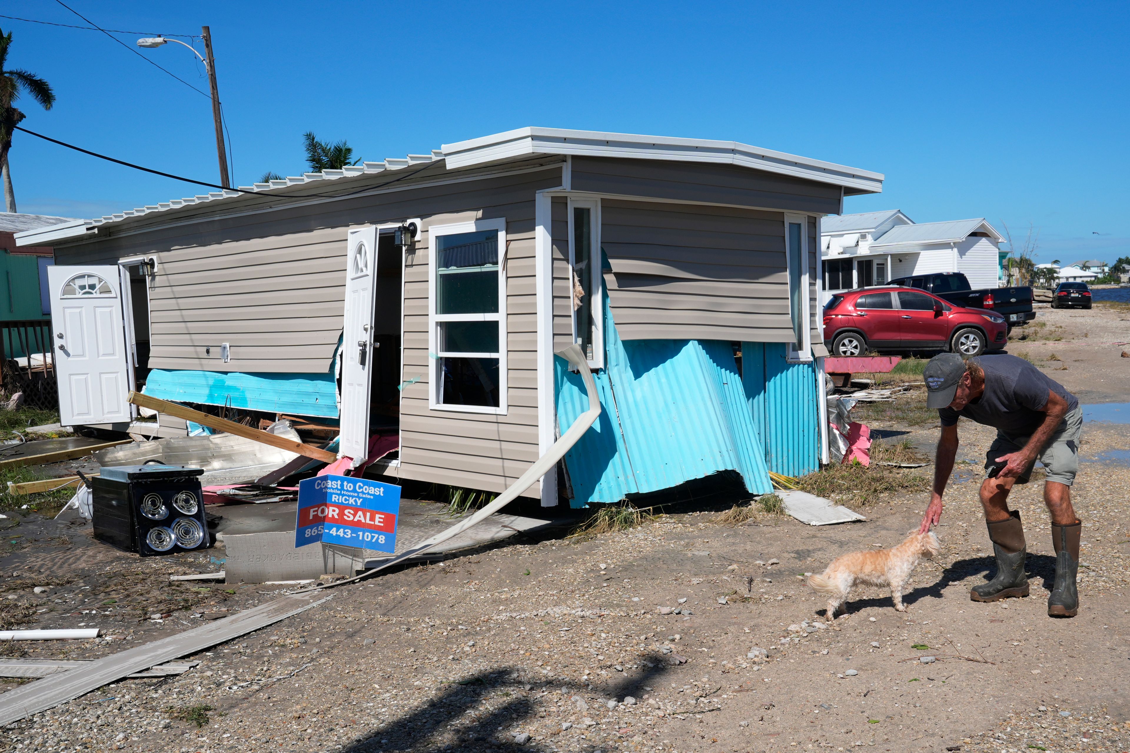 Rich Godar pets a neighbors dog next to a home destroyed by a tornado spurred by Hurricane Milton, Thursday, Oct. 10, 2024, in Matlacha, Fla. (AP Photo/Marta Lavandier)