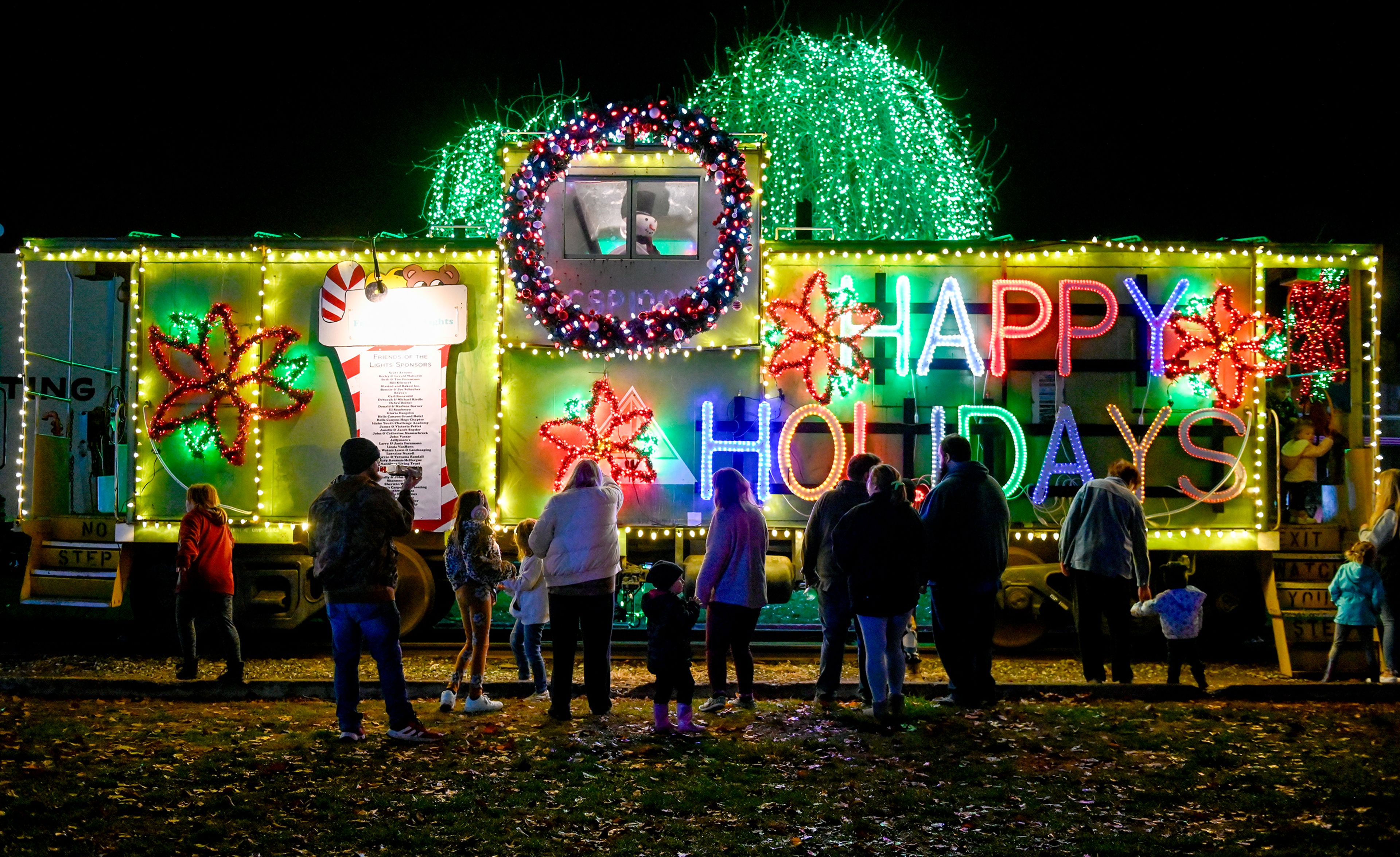 People stop to look at and take pictures with the Winter Spirit display Saturday at Locomotive Park in Lewiston.