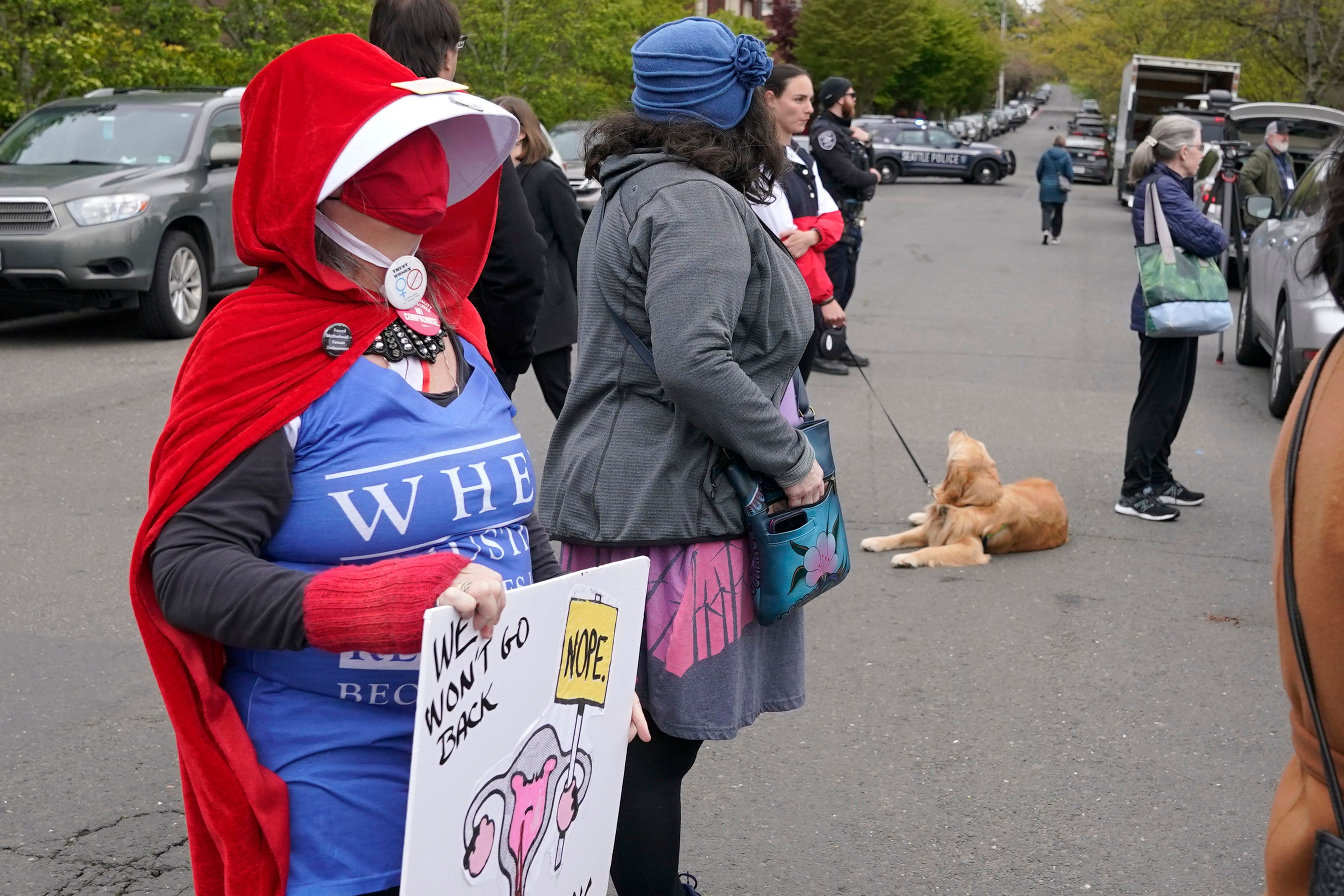 A person dressed as a character from "The Handmaid's Tale" holds a sign, Tuesday, May 3, 2022, during a rally at a park in Seattle in support of abortion rights. (AP Photo/Ted S. Warren)