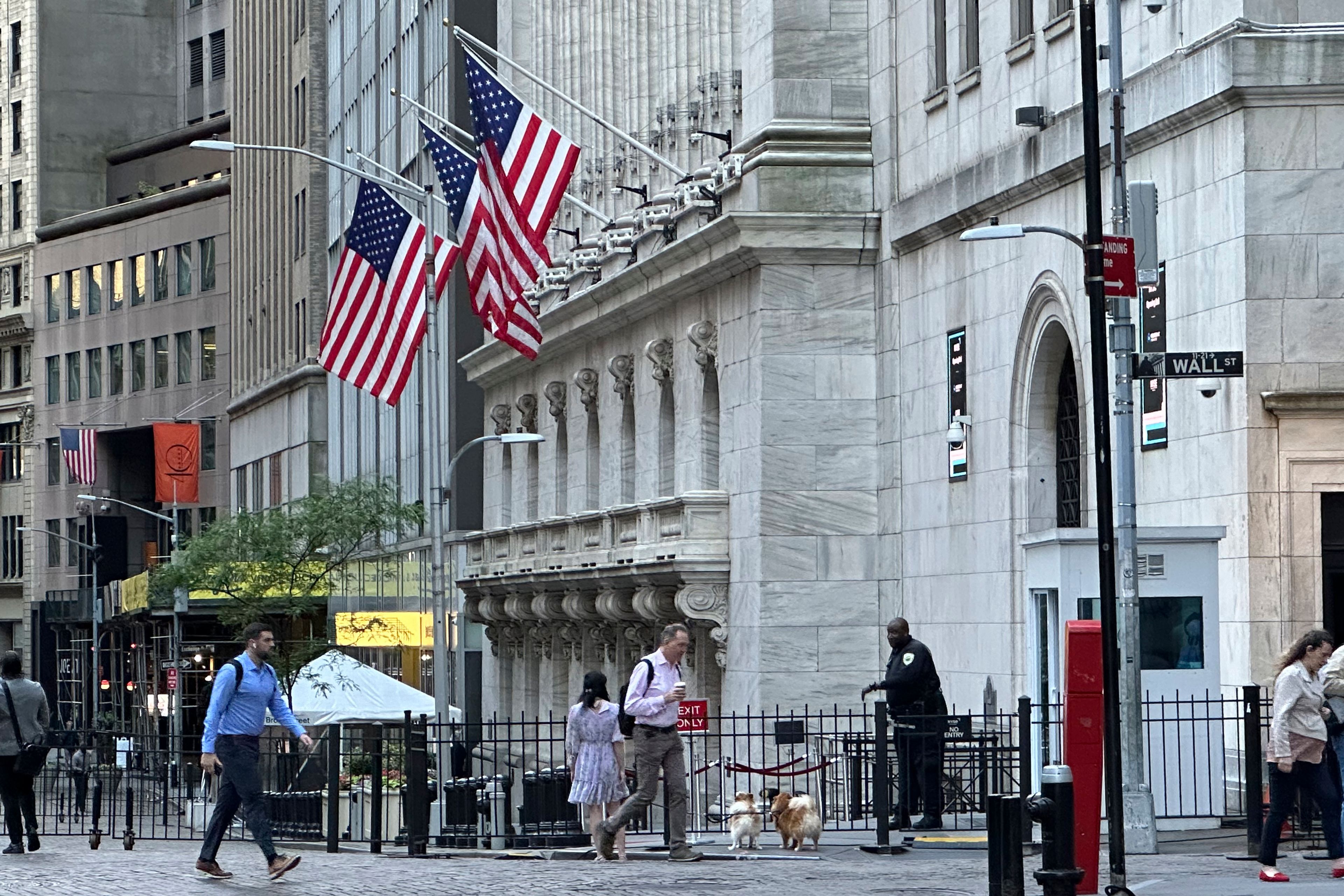 FILE - People pass the New York Stock Exchange on Wednesday, May 29, 2024, in New York. Some U.S. companies saw the trading of their shares temporarily halted Monday, June 3, including at least one whose price briefly fell nearly 100%, following a technical issue for some stocks listed on the New York Stock Exchange.