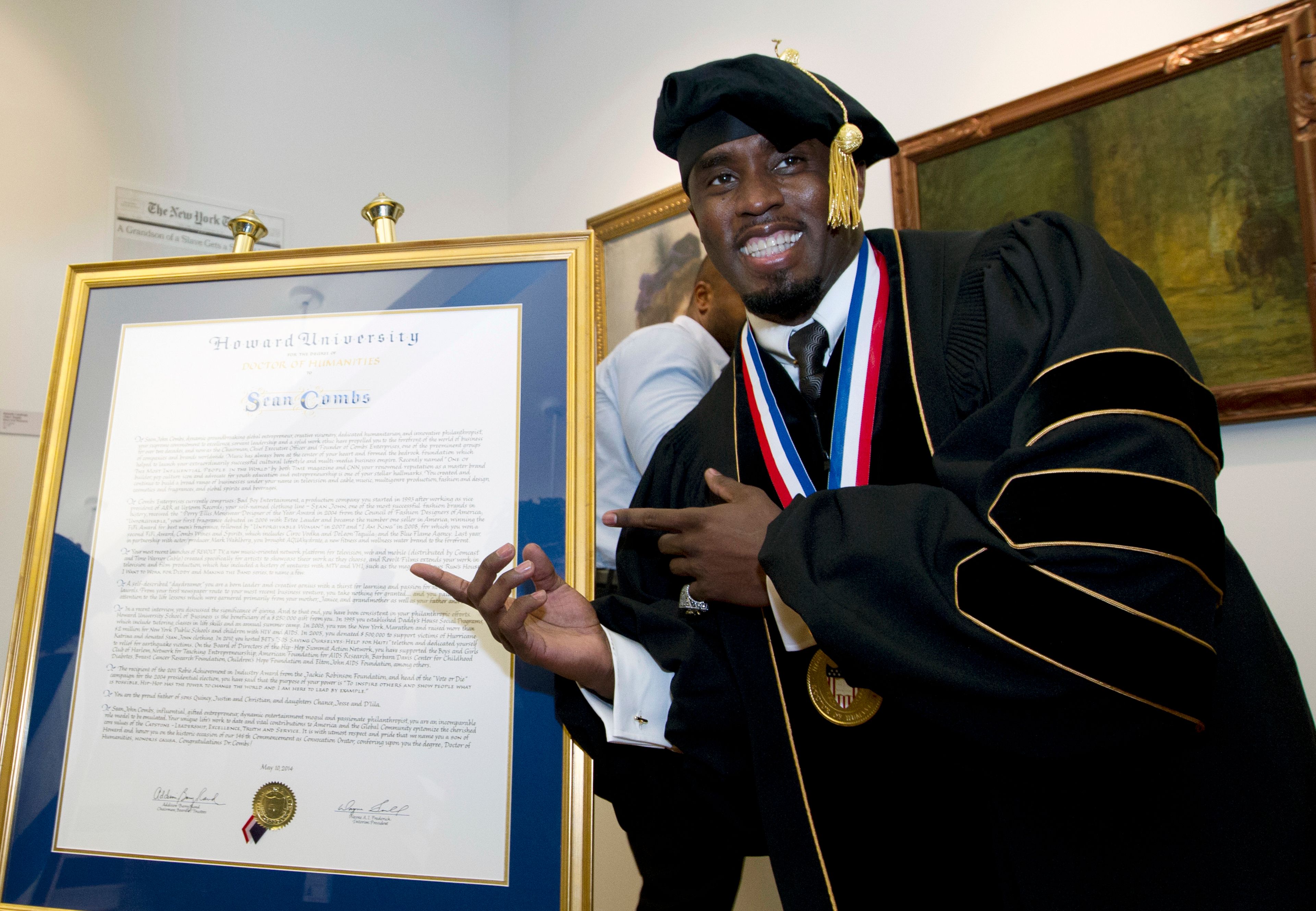 FILE - Entertainer and entrepreneur Sean Combs poses next to his honorary degree of Doctor of Humanities during the graduation ceremony at Howard University in Washington, Saturday, May 10, 2014. In a decision, Friday, June 7, 2024, Howard University is cutting ties to Combs, rescinding the honorary degree that was awarded to him and disbanding a scholarship program in his name.