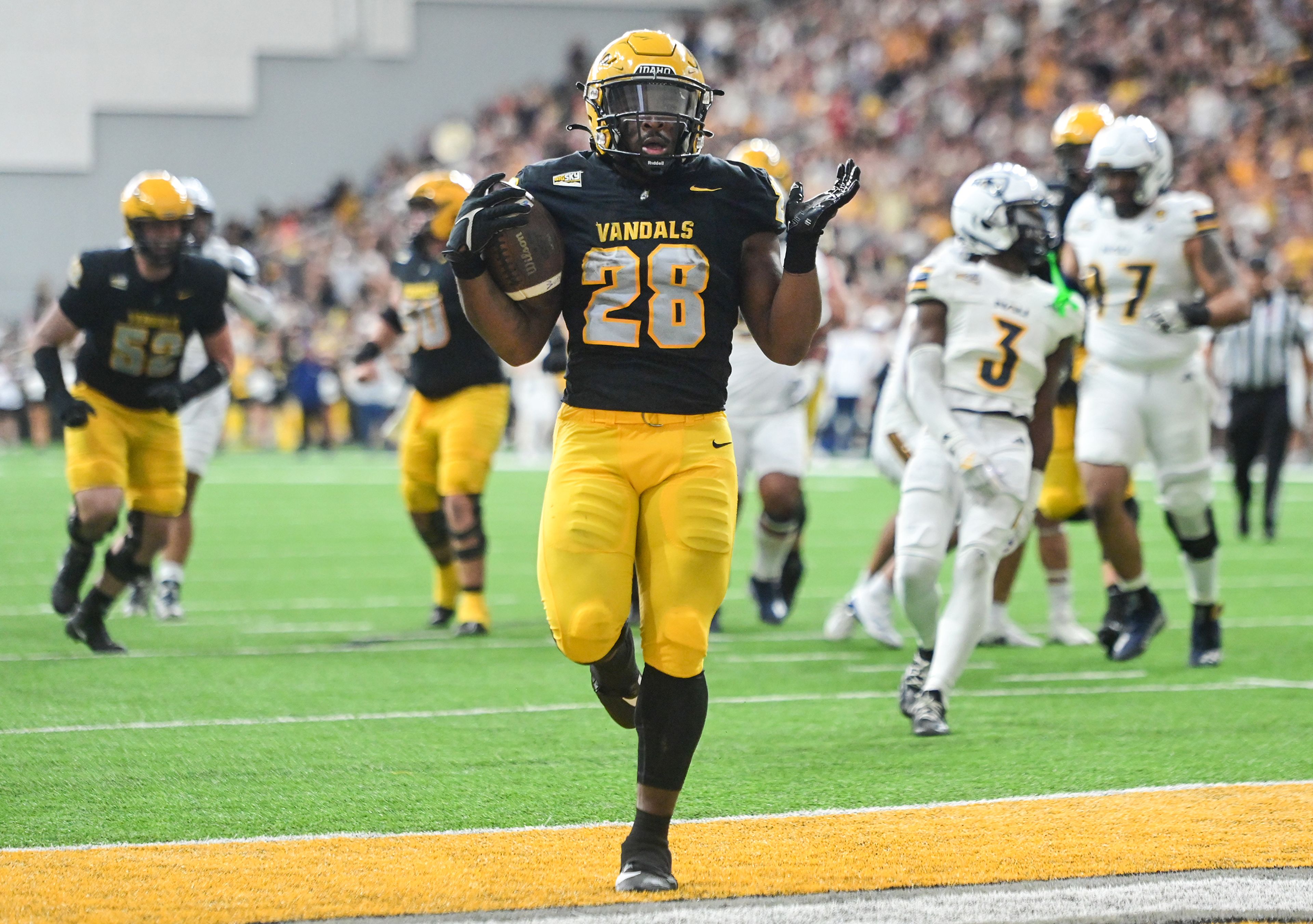 Idaho running back Nate Thomas raises his palms as he carries the ball into the end zone for a touchdown against Northern Arizona Saturday at the P1FCU Kibbie Dome in Moscow.,