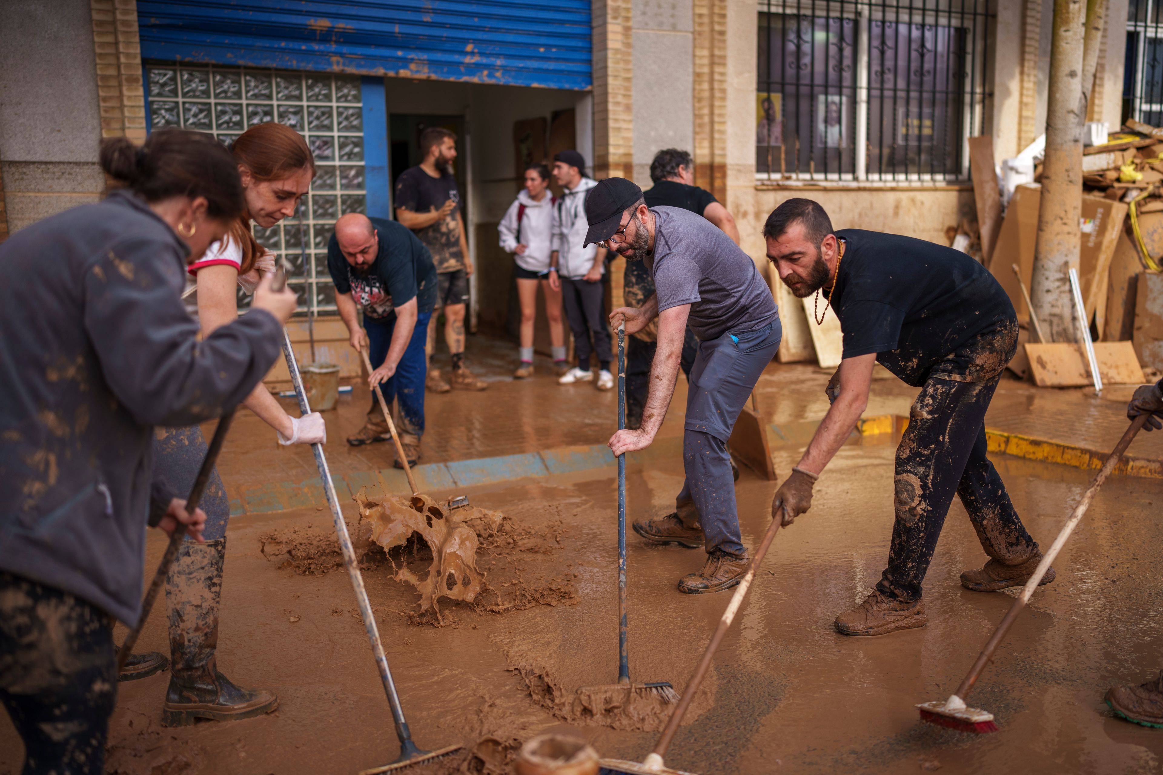 Mud-caked volunteers clean flood debris