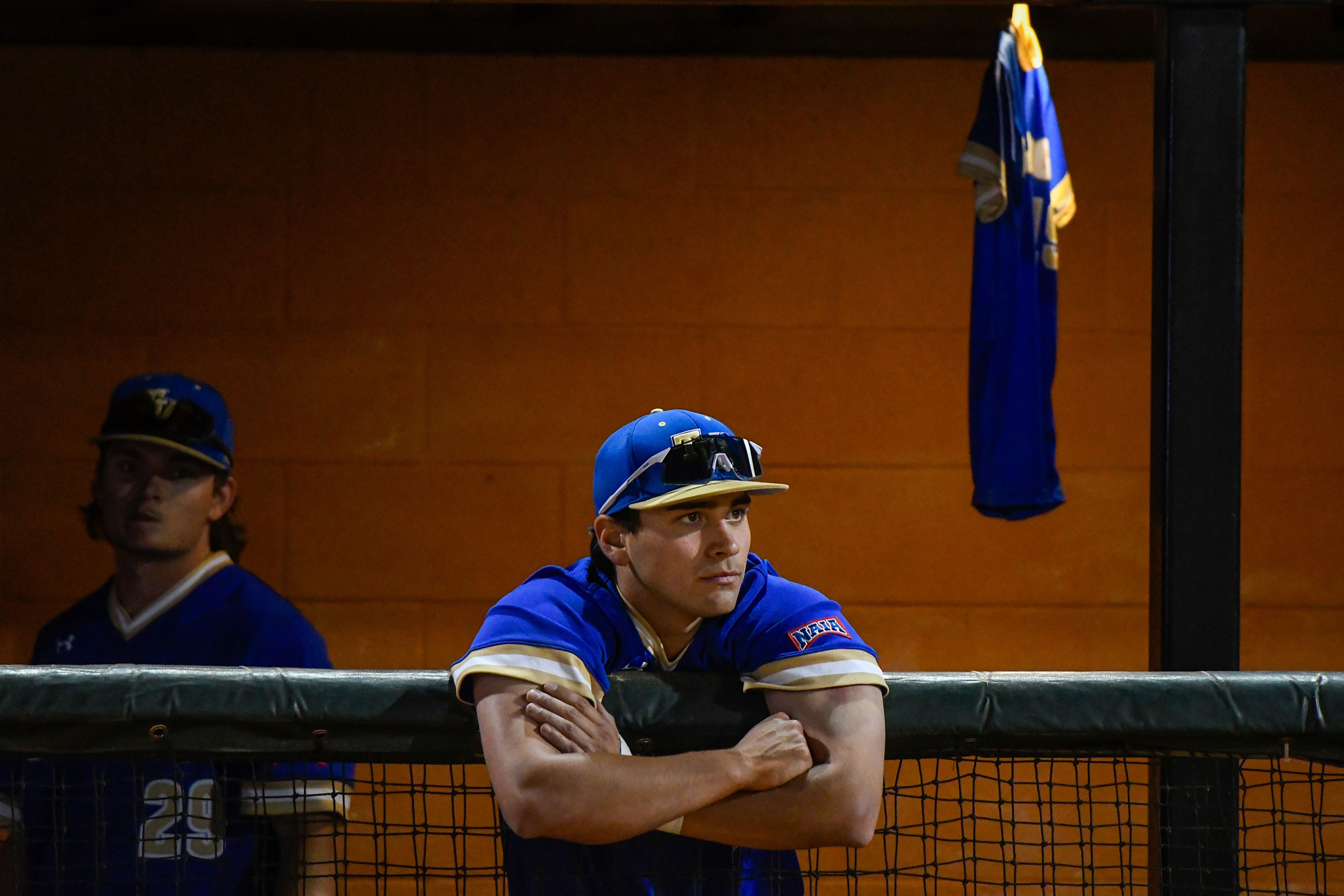 A Tennessee Wesleyan player leans over the edge of the dugout as Hope International takes the field to celebrate its championship win in the NAIA World Series on Friday at Harris Field in Lewiston.