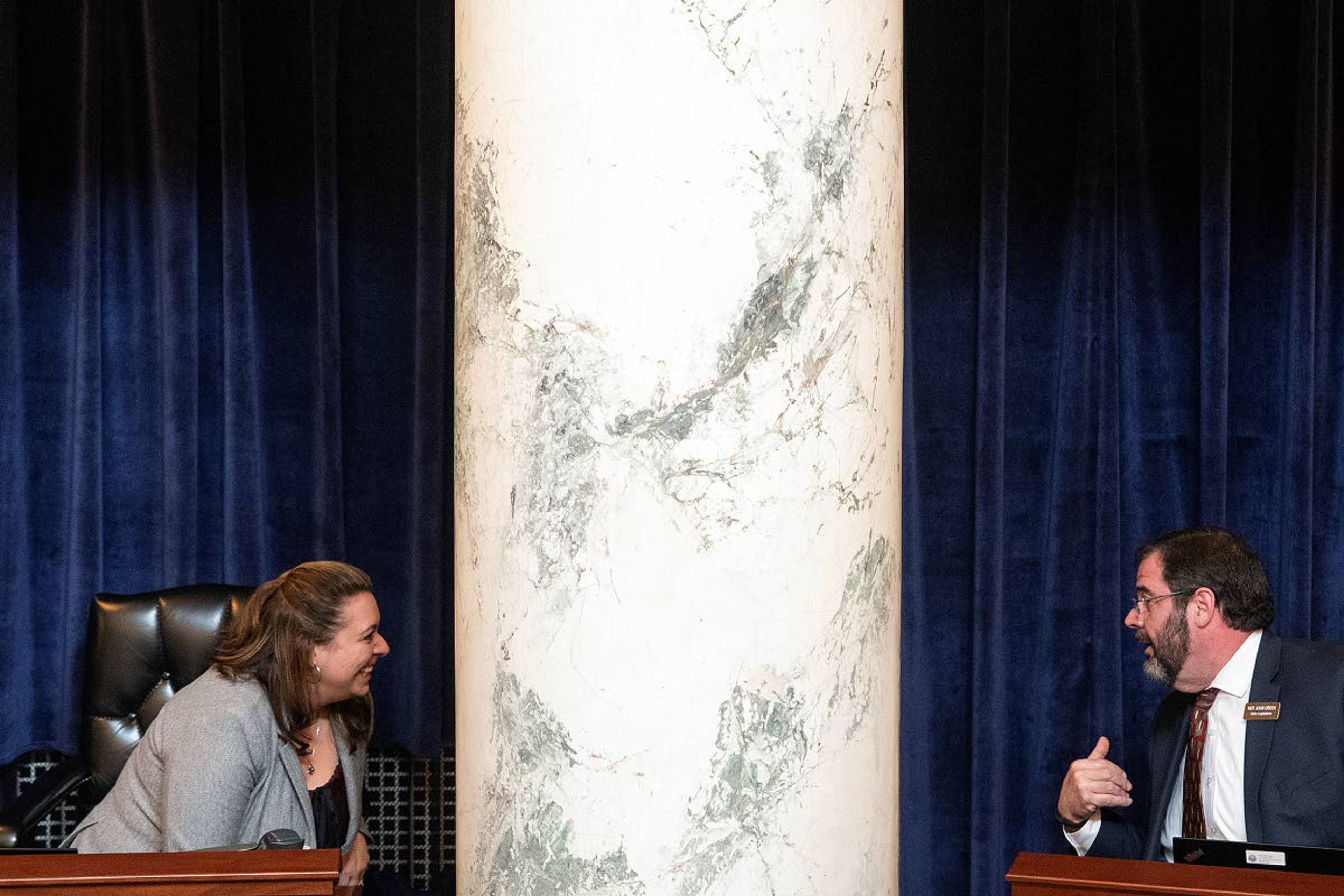 First-term legislators Rep. Brooke Green, D-Boise, left, and Rep. John Green, R-Post Falls, talk around a column from the desks in the back row of the Idaho House of Representatives in Boise.