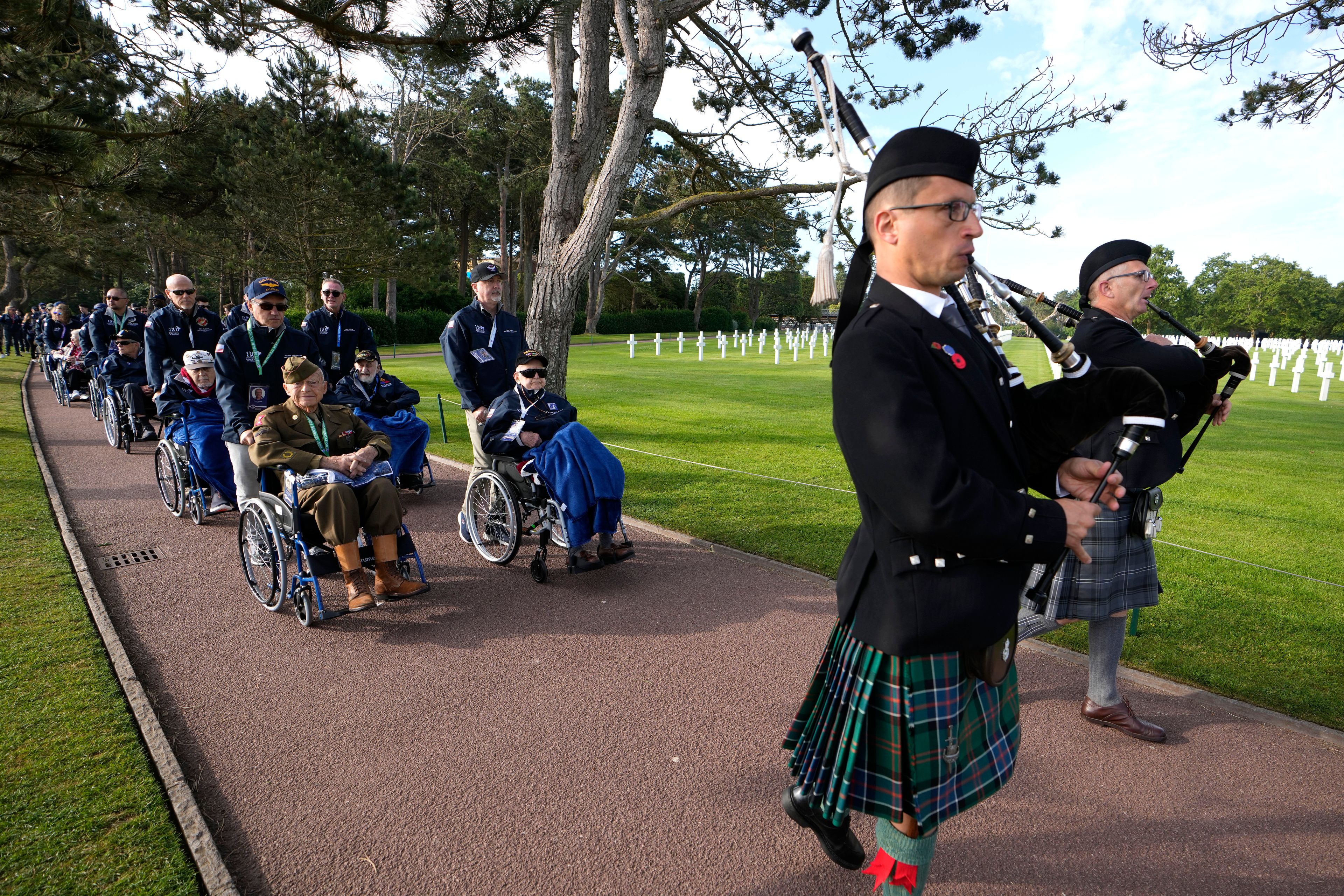 World War II and D-Day veterans are led by two pipers as they prepare to visit graves at the Normandy American Cemetery in Colleville-sur-Mer, Tuesday, June 4, 2024. World War II veterans from across the United States as well as Britain and Canada are in Normandy this week to mark 80 years since the D-Day landings that helped lead to Hitler's defeat. (AP Photo/Virginia Mayo)