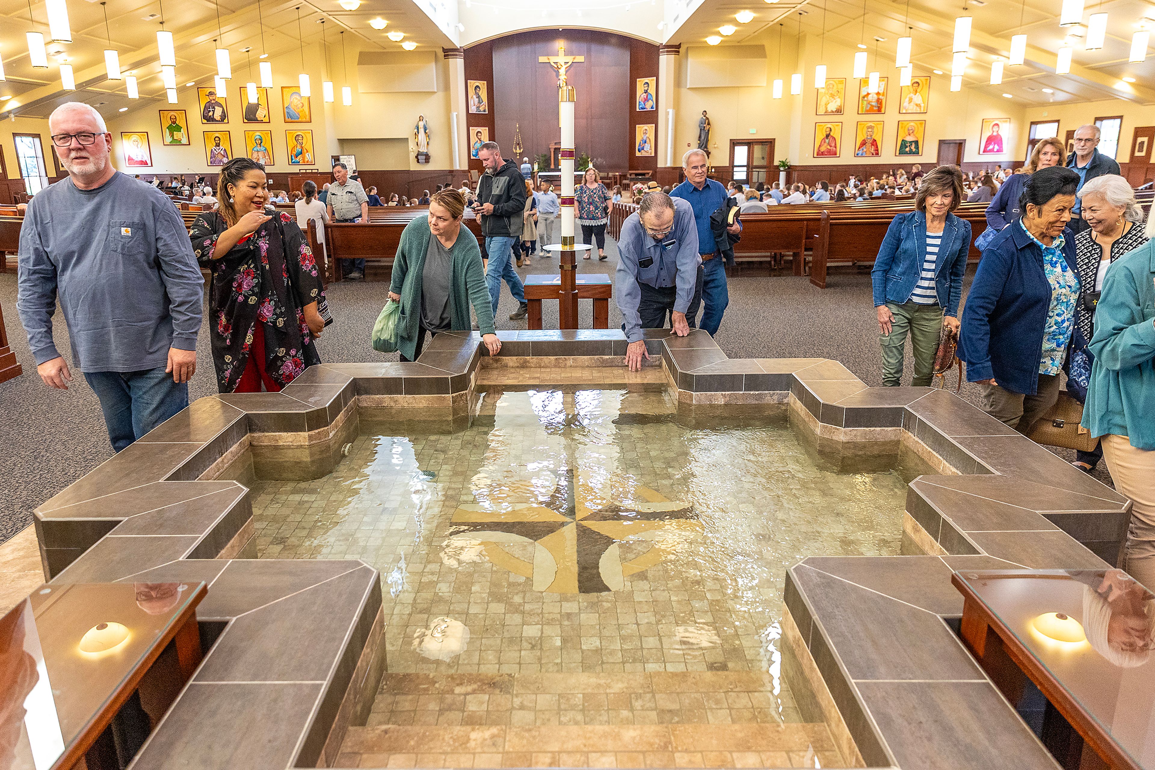 Parishioners dip their hands in the batismal font to make the sign of the cross with holy water Wednesday at All Saints Catholic Church in the Lewiston Orchards.