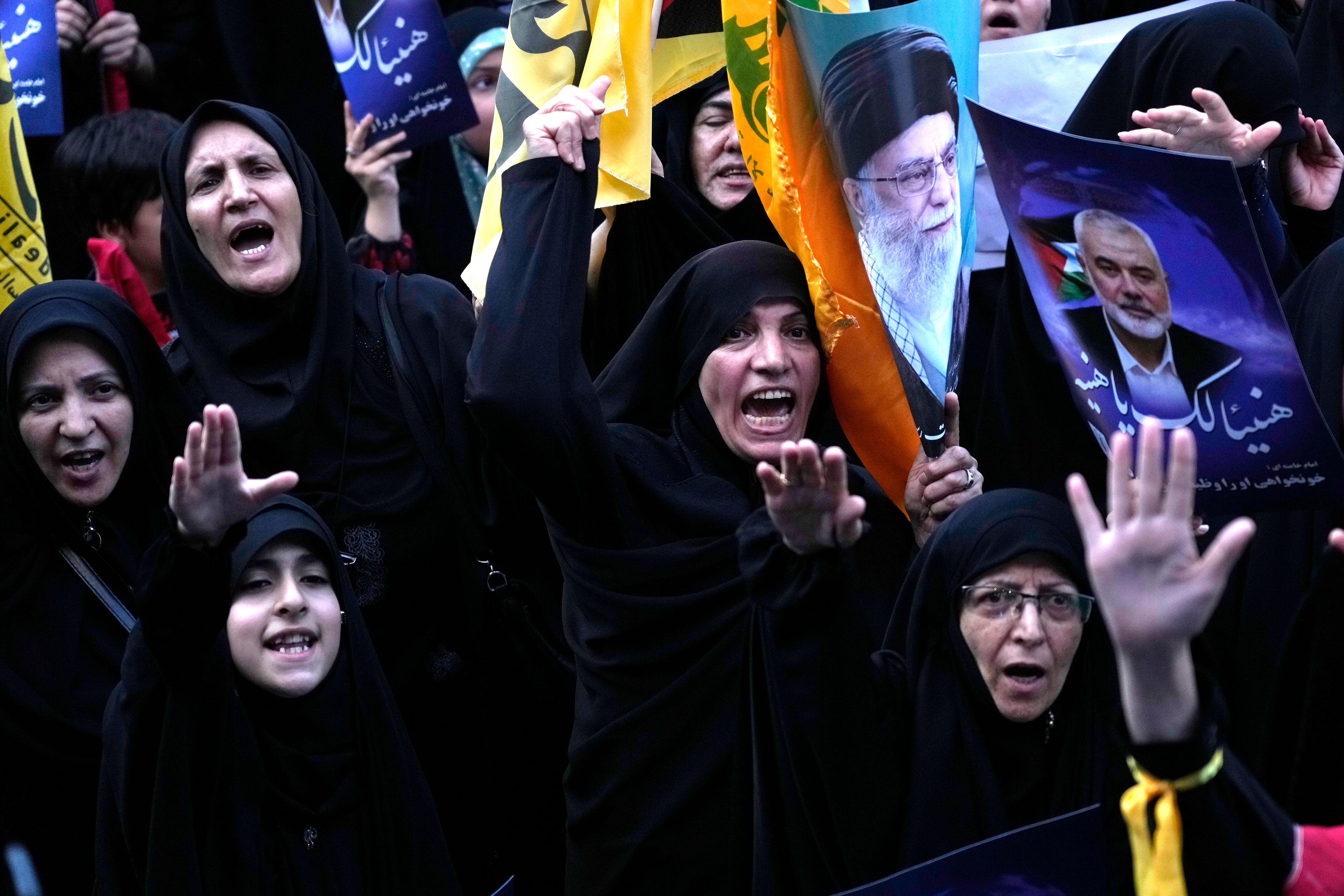 Iranian protesters chant slogans as they hold posters of the Supreme Leader Ayatollah Ali Khamenei, second right, and Hamas leader Ismail Haniyeh, right, with sign which reads in Arabic: "Congratulations Haniyeh!" in a demonstration to condemn killing of Haniyeh at Felestin (Palestine) Sq. in Tehran, Iran, Wednesday, July 31, 2024. Haniyeh was assassinated in Tehran, Iran's paramilitary Revolutionary Guard said early Wednesday. (AP Photo/Vahid Salemi)