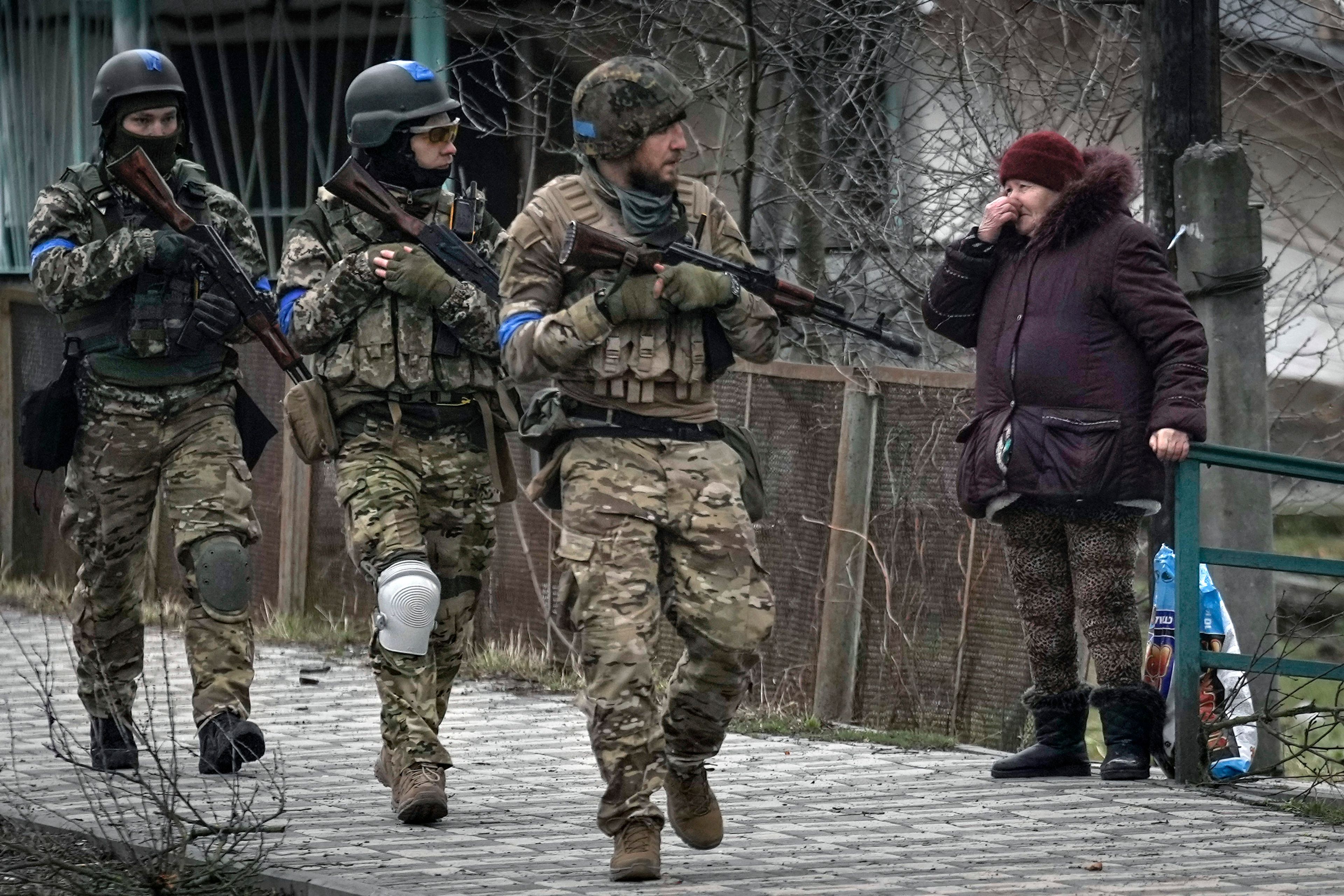 A woman looks at Ukrainian servicemen walking in the formerly Russian-occupied Kyiv suburb of Bucha, Ukraine, Saturday, April 2, 2022. As Russian forces pull back from Ukraine's capital region, retreating troops are creating a "catastrophic" situation for civilians by leaving mines around homes, abandoned equipment and "even the bodies of those killed," President Volodymyr Zelenskyy warned Saturday.(AP Photo/Vadim Ghirda)