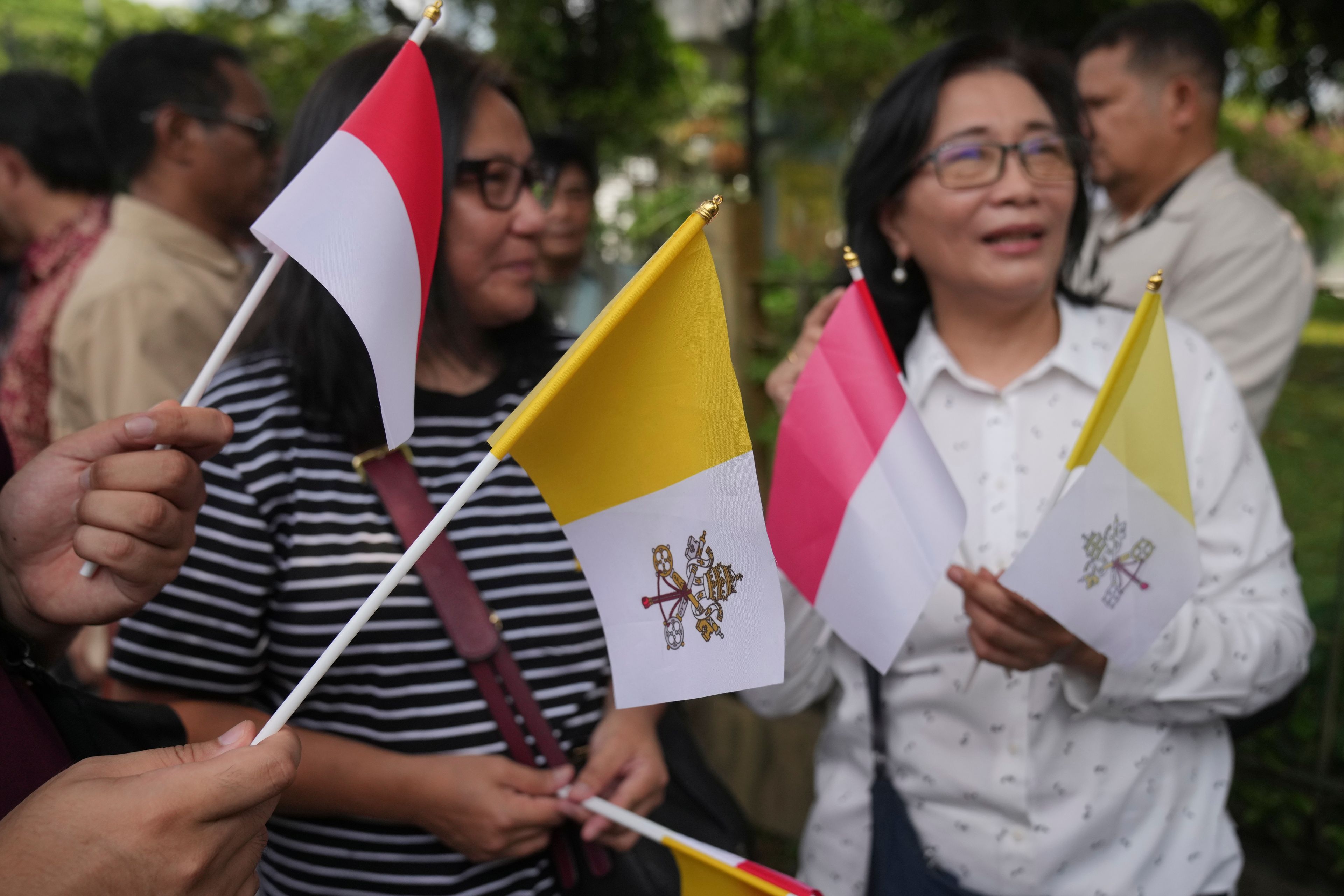 People hold Indonesian and Vatican flags as they welcome the arrival of Pope Francis outside the Vatican Embassy in Jakarta, Indonesia, Tuesday, Sept. 3, 2024.