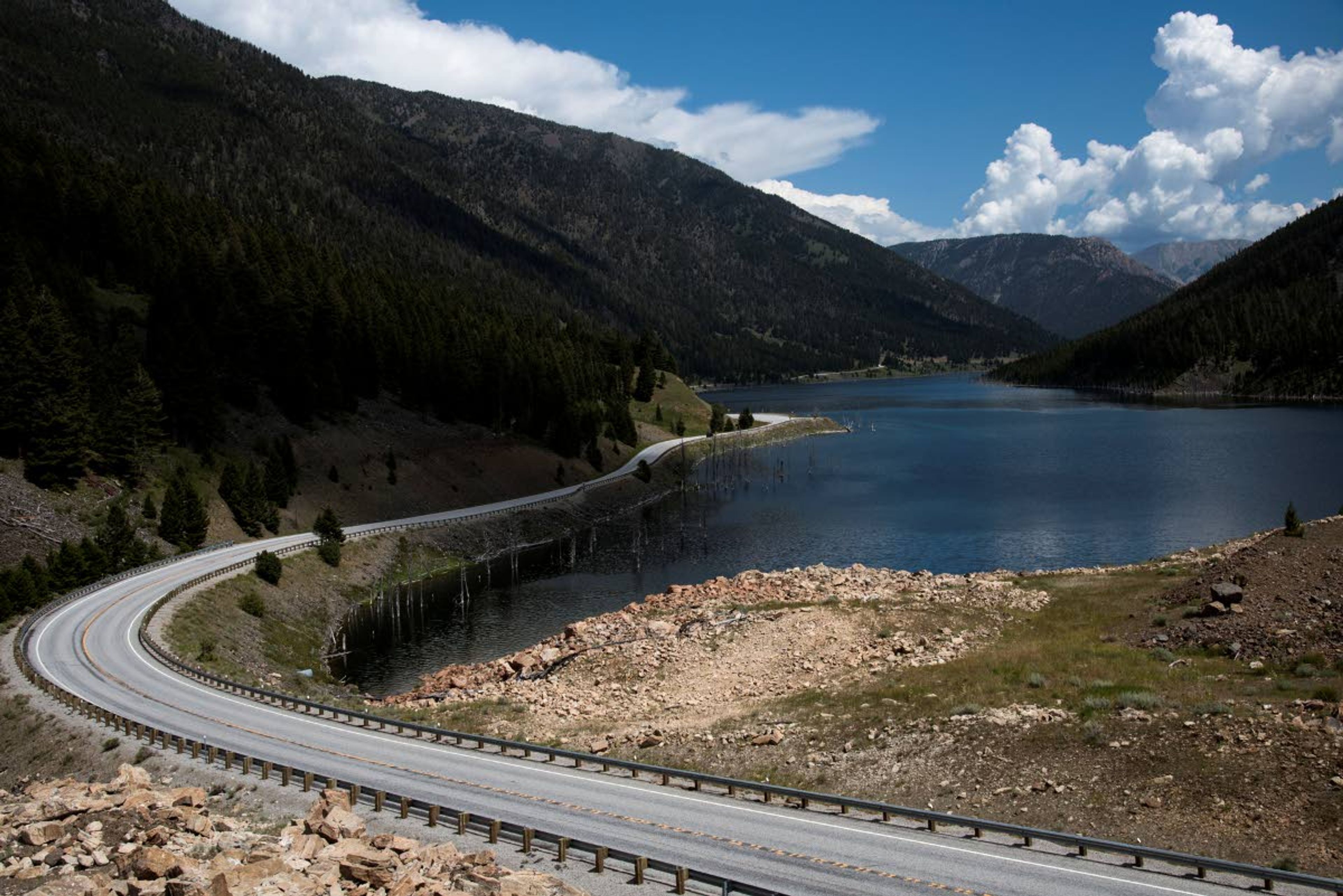 Highway 287 curves around the perimeter of Earthquake Lake on Aug. 1, 2019. An earthquake had disrupted the full-moon night of Aug. 17, 1959, turning it chaotic and terrifying. The quake had a magnitude of 7.3, and it remains the largest to hit the region. The landslide also stopped the river. The water backed up and spread out, turning a swath of canyon into an ominous lake. (Rachel Leathe/Bozeman Daily Chronicle via AP)