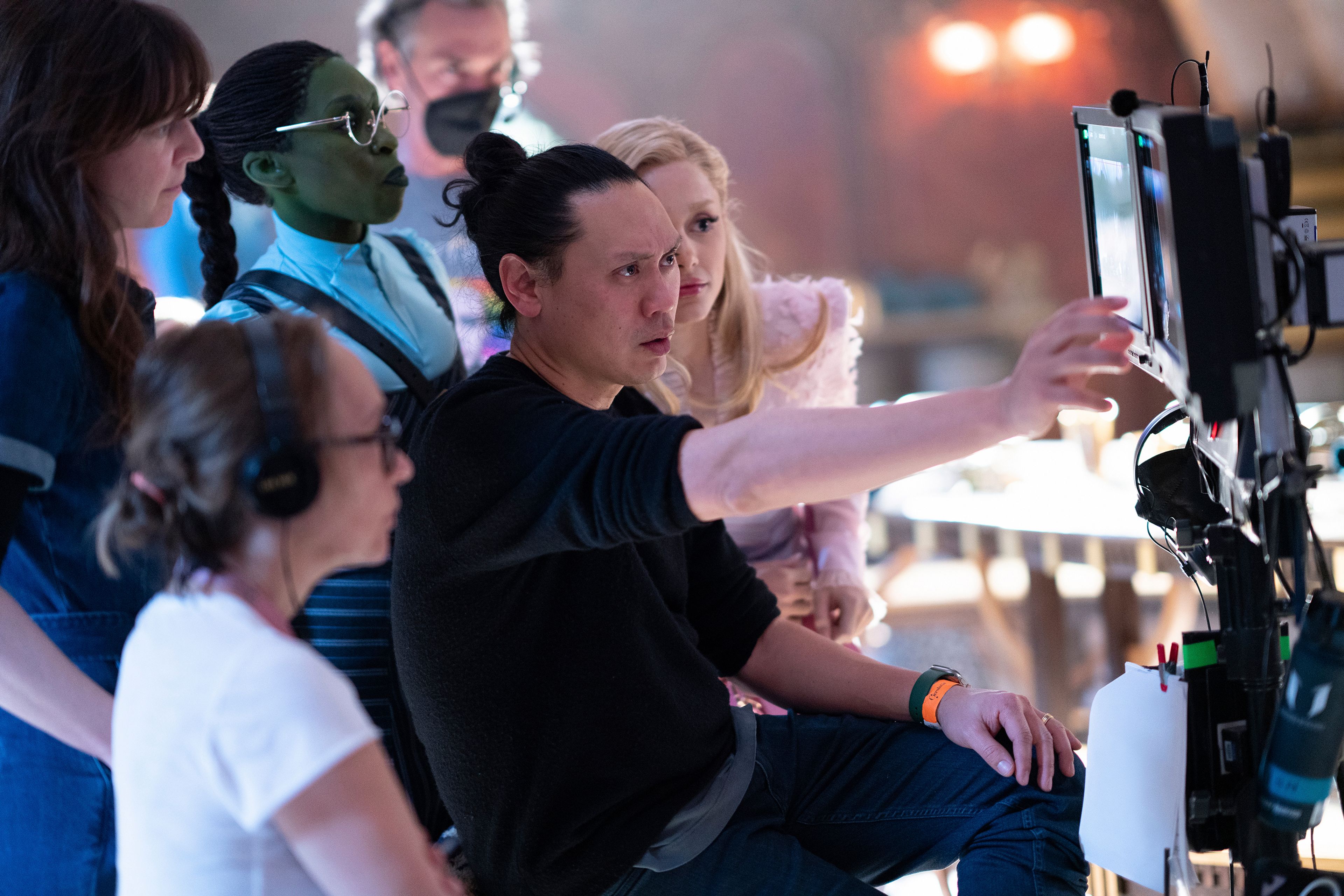 This image released by Universal Pictures shows director Jon M. Chu, center, on the set of "Wicked."