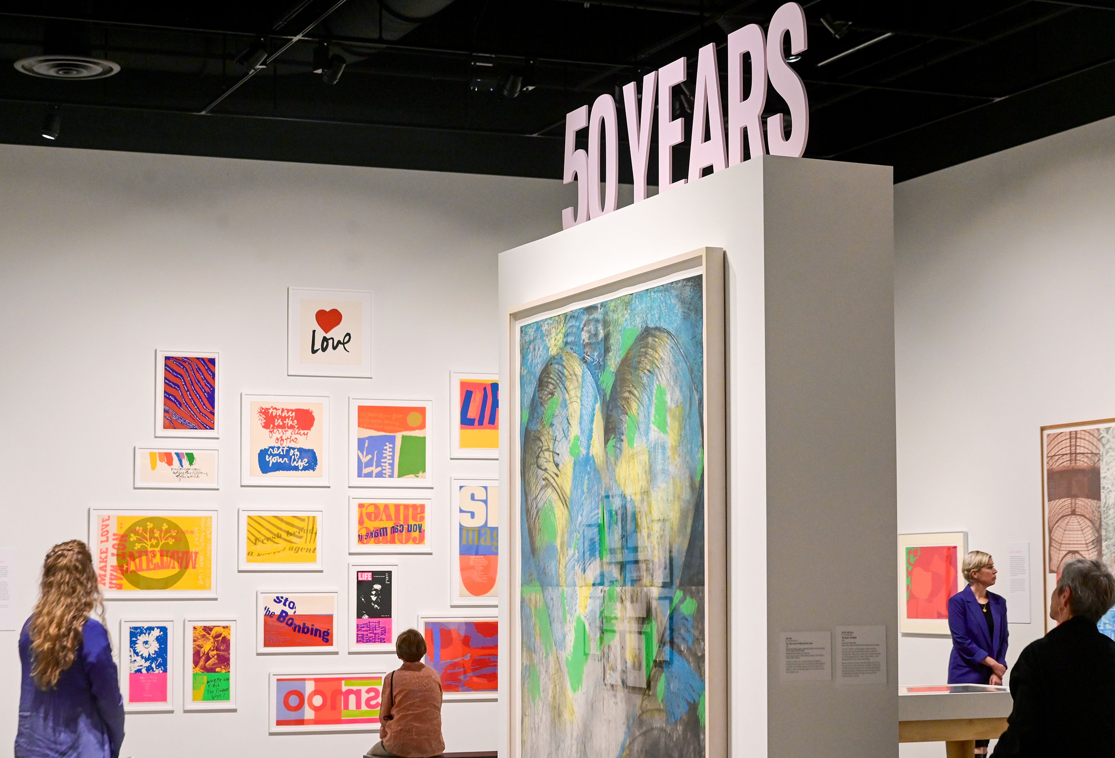 A tribute to the Washington State University art museums 50th anniversary sits Thursday above artwork of a current exhibit called "The Art of Food" at the Jordan Schnitzer Museum of Art at WSU in Pullman. Crowds circulated the museum before a reception and book release to celebrate the anniversary.