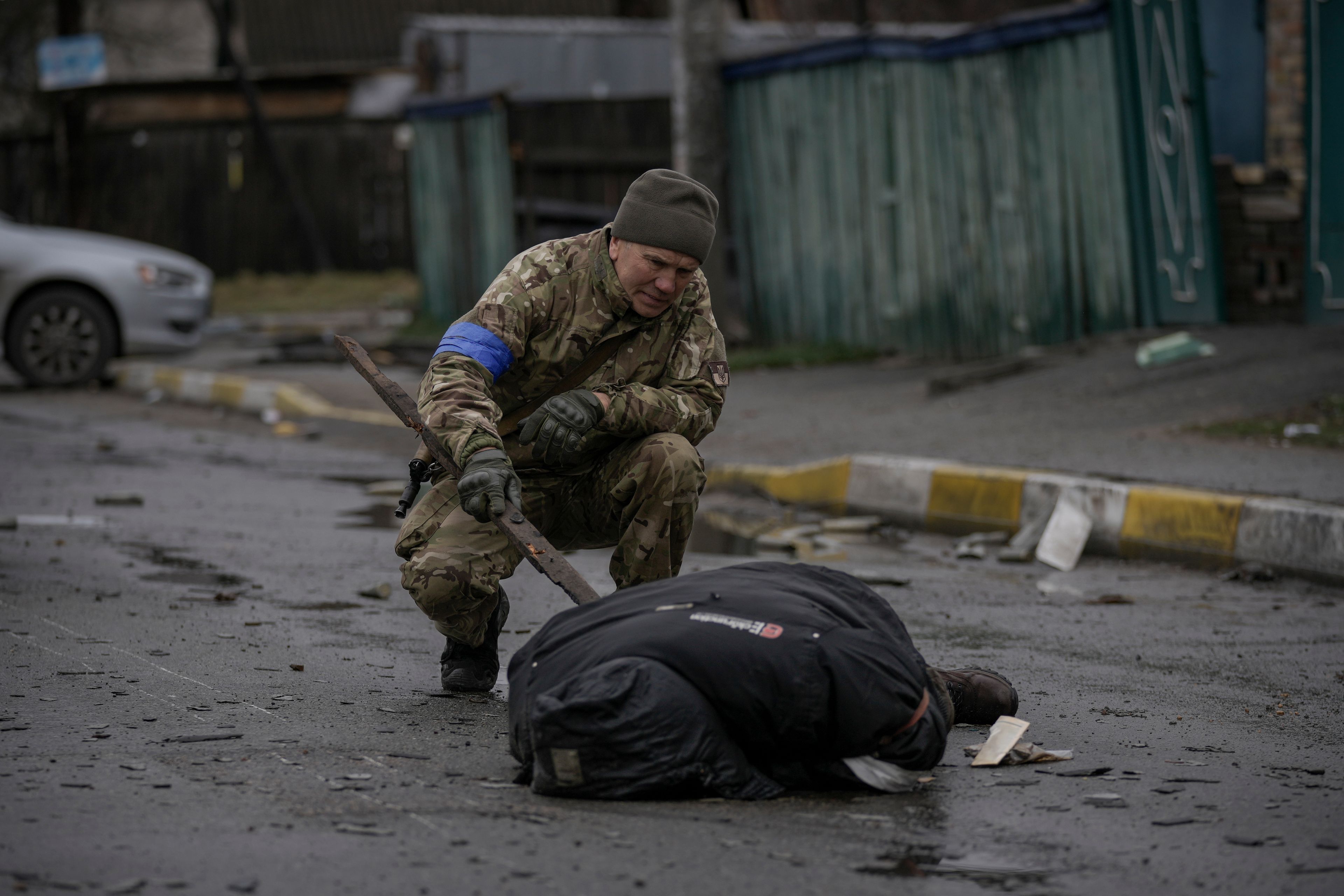 A Ukrainian serviceman checks the dead body of a civilian for booby traps in the formerly Russian-occupied Kyiv suburb of Bucha, Ukraine, Saturday, April 2, 2022. As Russian forces pull back from Ukraine's capital region, retreating troops are creating a "catastrophic" situation for civilians by leaving mines around homes, abandoned equipment and "even the bodies of those killed," President Volodymyr Zelenskyy warned Saturday.(AP Photo/Vadim Ghirda)