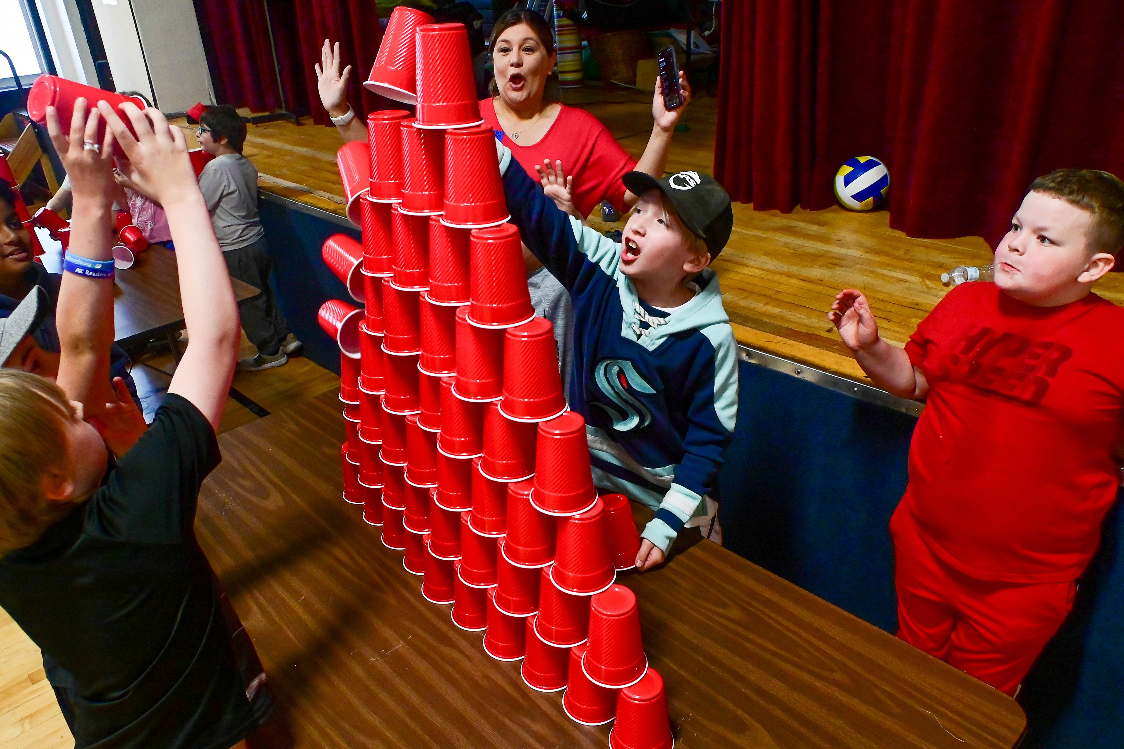 Jack Jones, center, and Lucas Foram, right, third graders, react to their team’s cup tower falling as they play a version of Minute to Win It at Russell Elementary’s final day of school field day on Wednesday.