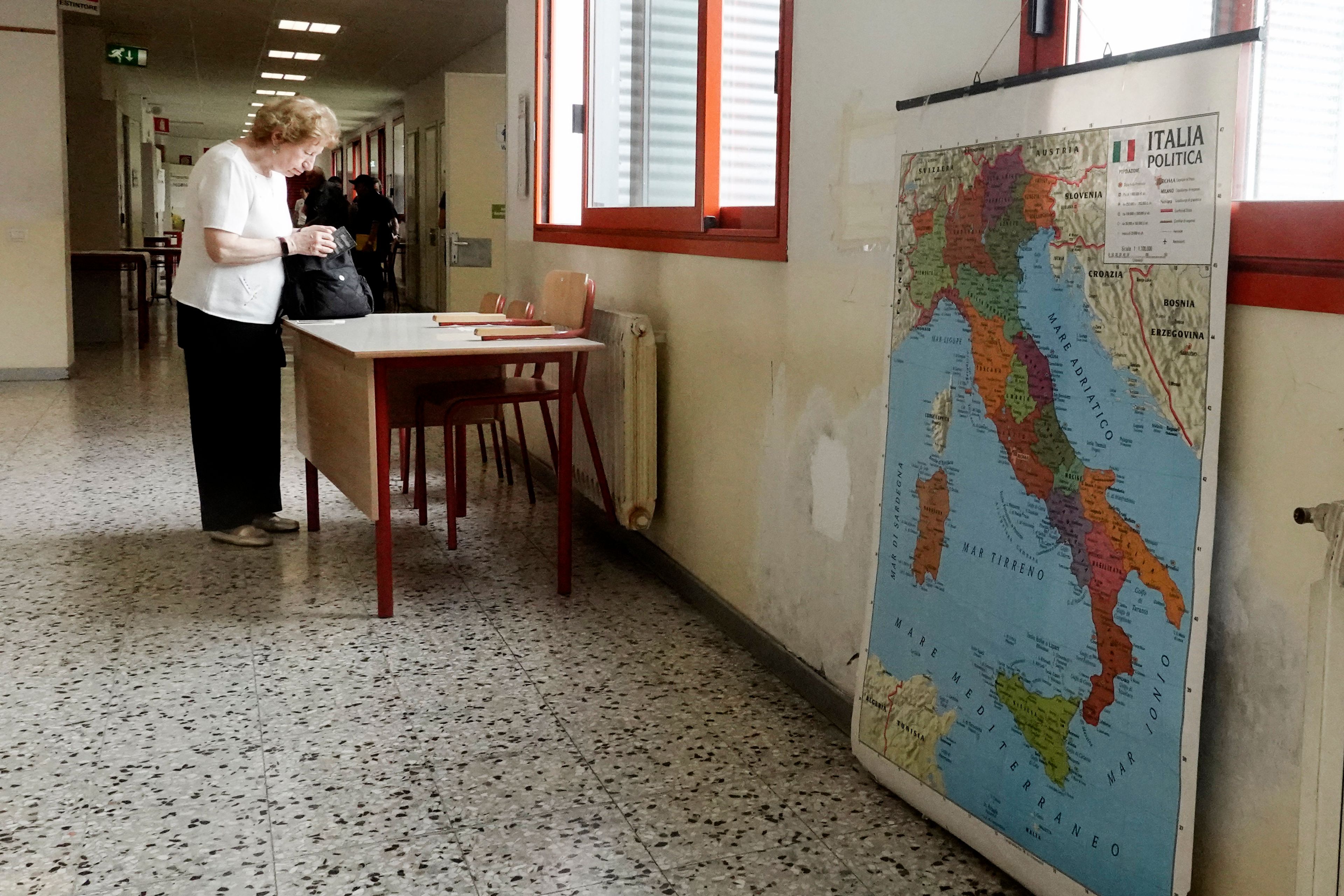 An elderly woman checks her voting paper before entering a polling station in Milan, Italy, Sunday, June 9, 2024. Tens of millions across the European Union were voting in EU parliamentary elections on Sunday in a massive exercise of democracy that is expected to shift the bloc to the right and redirect its future.