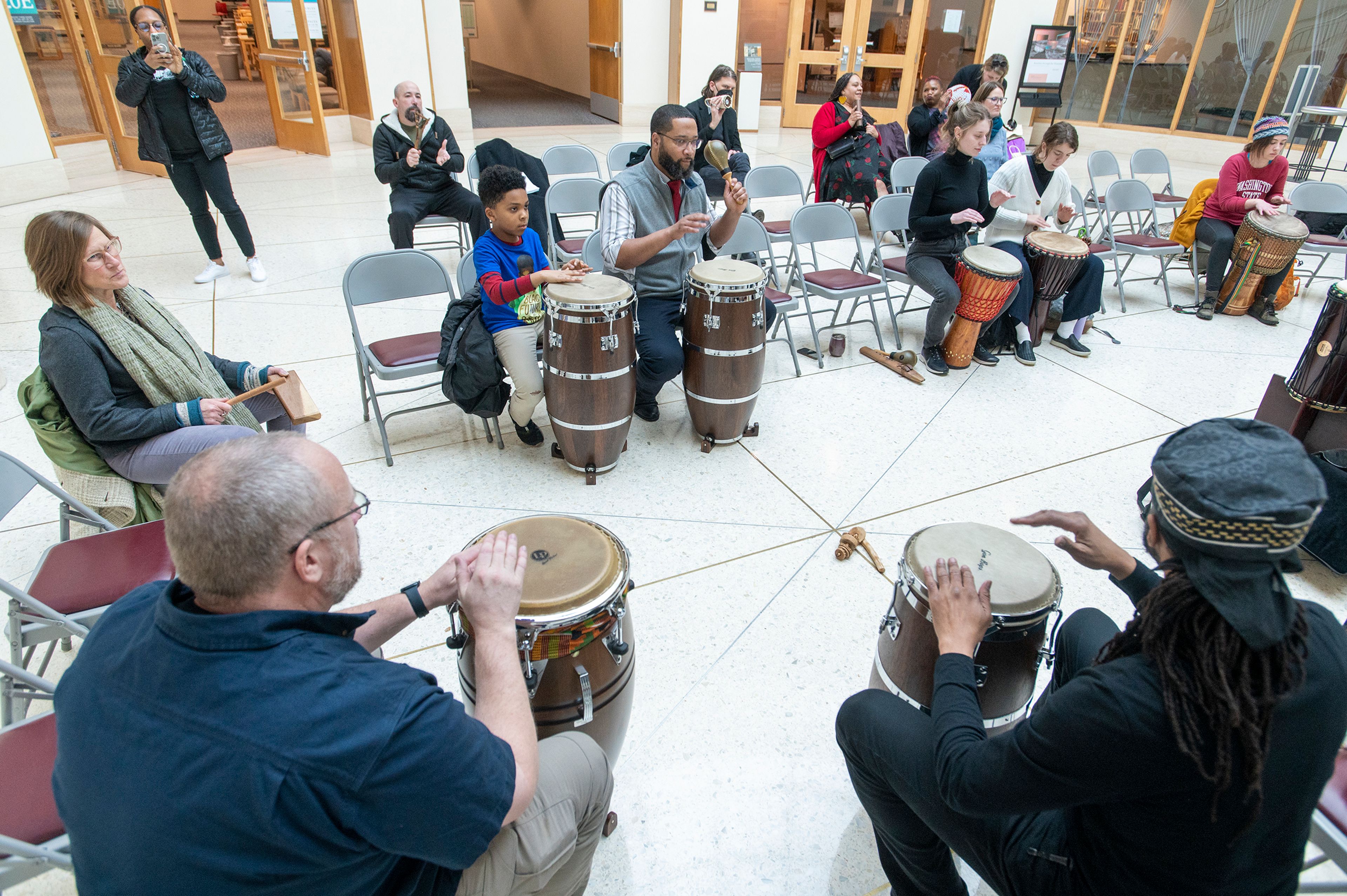 Visitors gather to listen and participate in a drum circle Tuesday at Washington State University’s Terrell Library Atrium in Pullman for the National Day of Racial Healing.