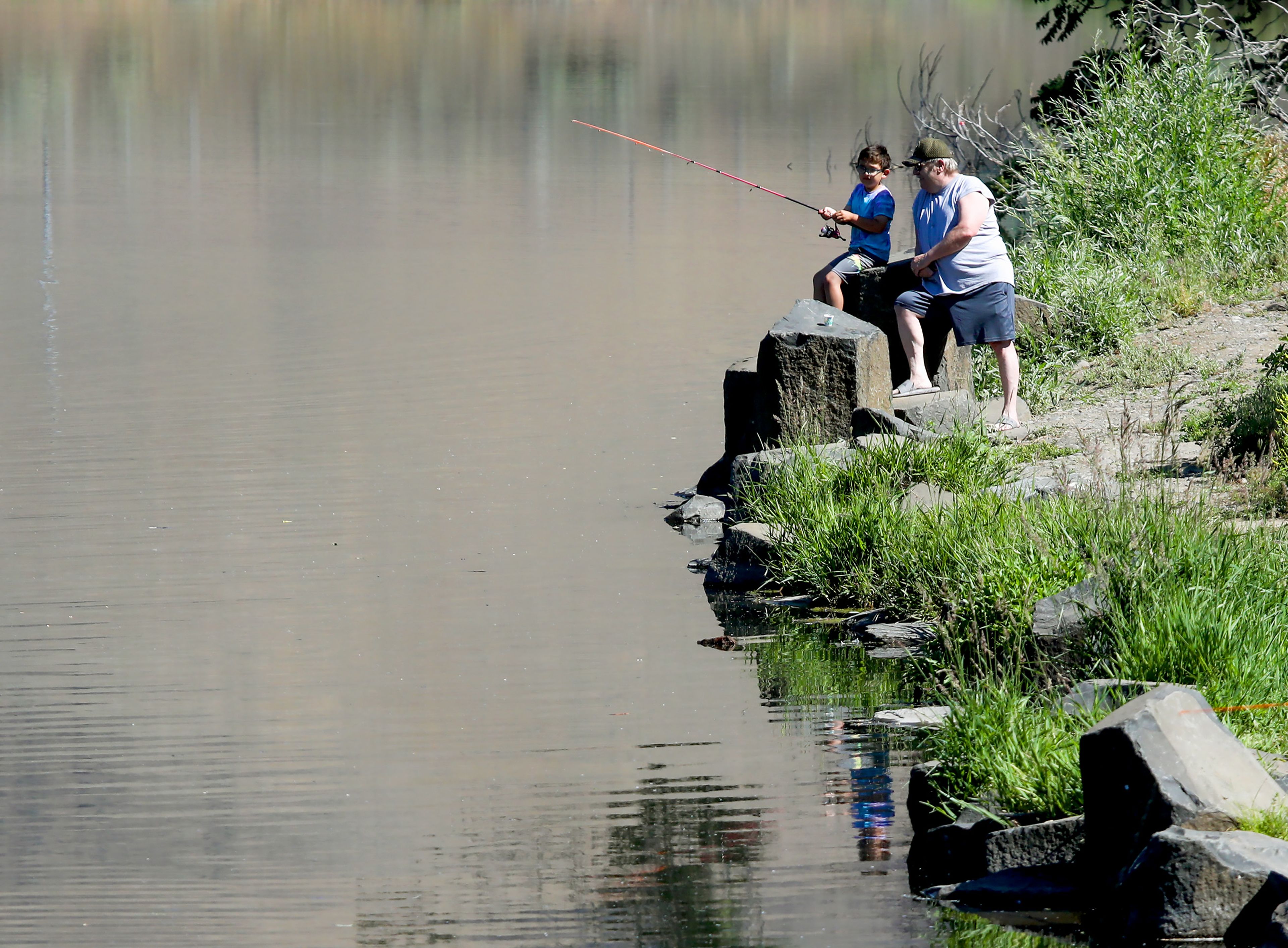 Louie Palmer, 8, and grandfather Rick Palmer fish along the edge of Kiwanis Park Pond during Idaho's Free Fishing Day on Saturday in Lewiston.