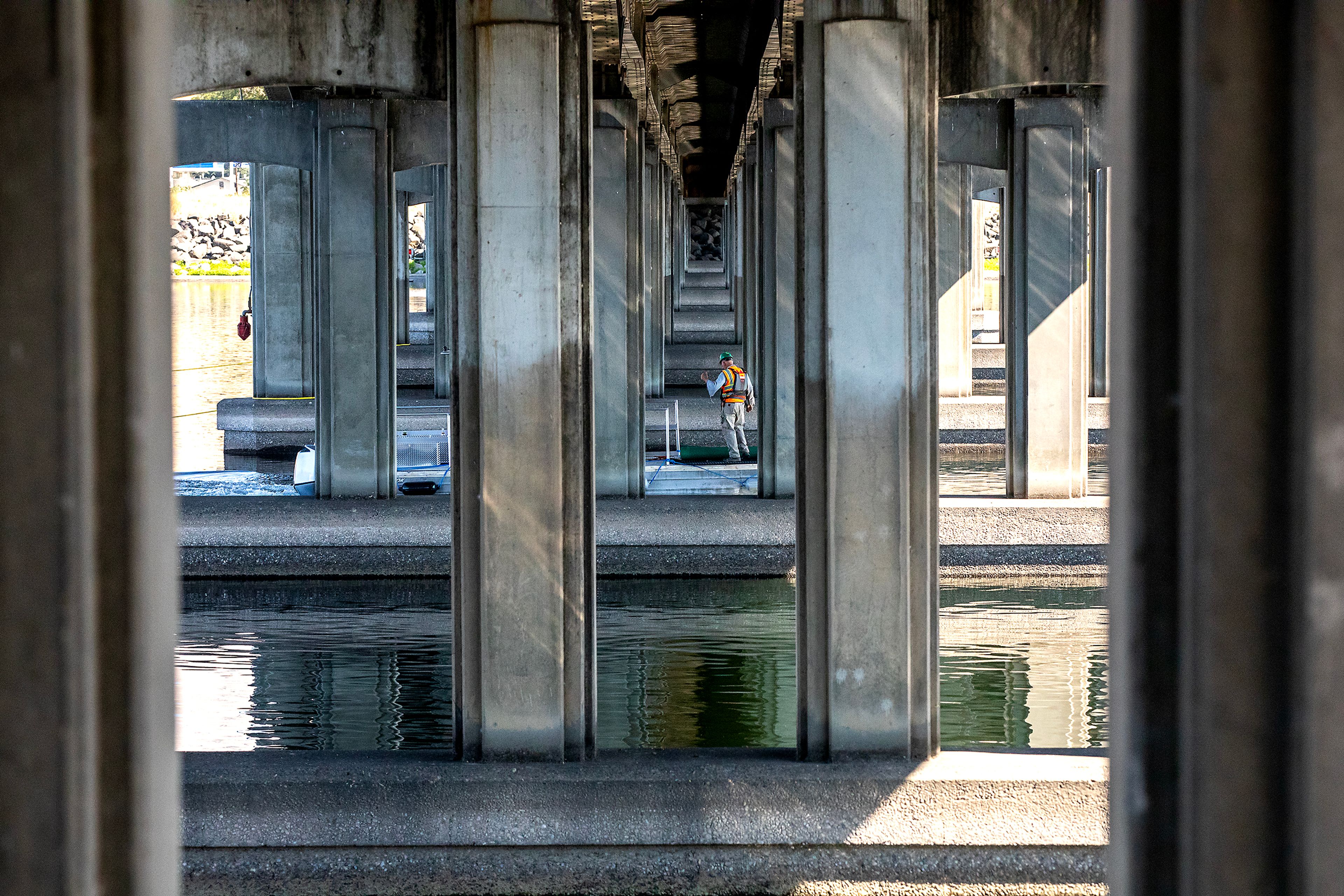 A workers stands on a boat as it passes under the Memorial Bridge Friday in Lewiston.