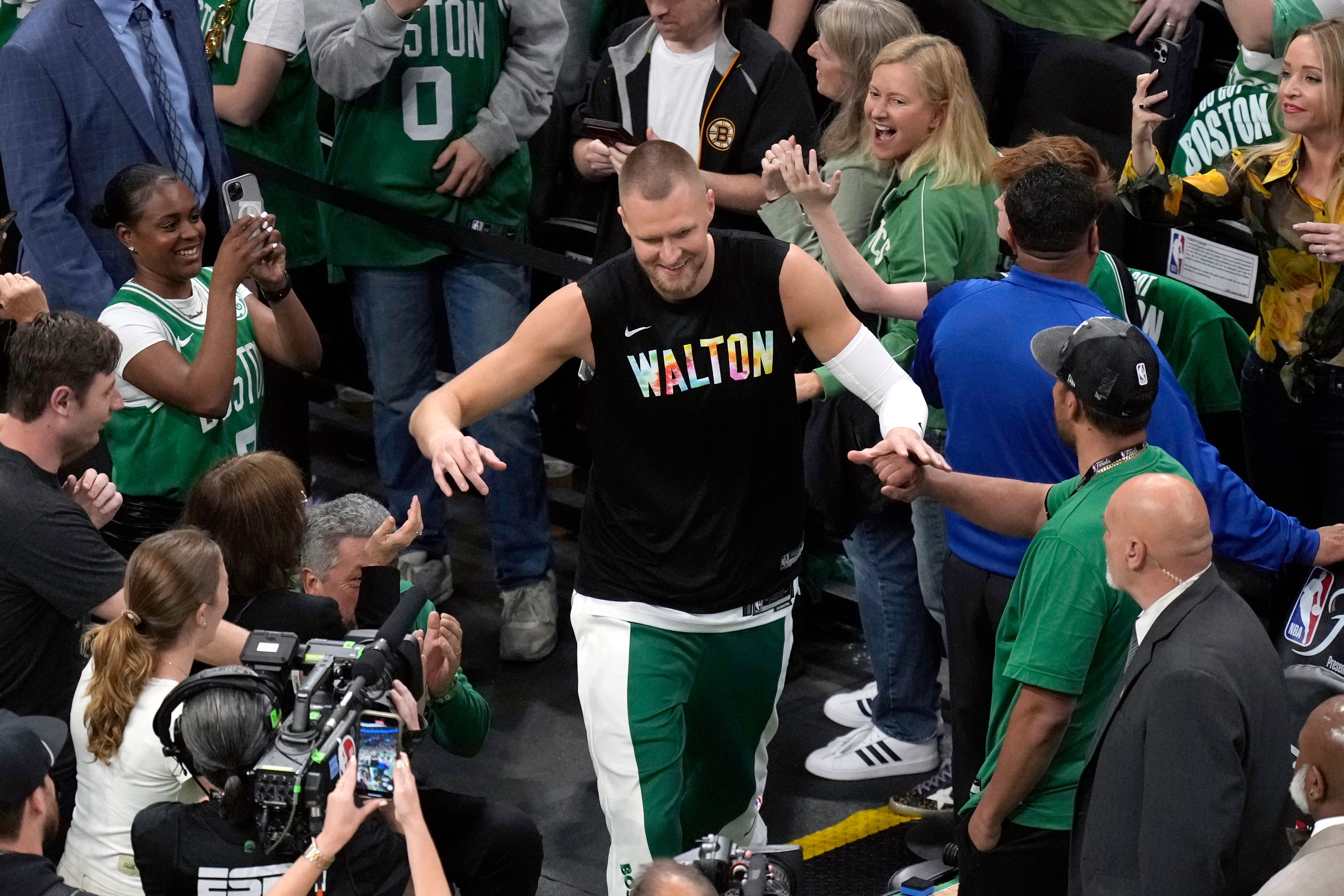 Boston Celtics center Kristaps Porzingis heads to the court while wearing a warmup shirt honoring basketball great Bill Walton before Game 1 of the basketball team's NBA Finals against the Dallas Mavericks, Thursday, June 6, 2024, in Boston.