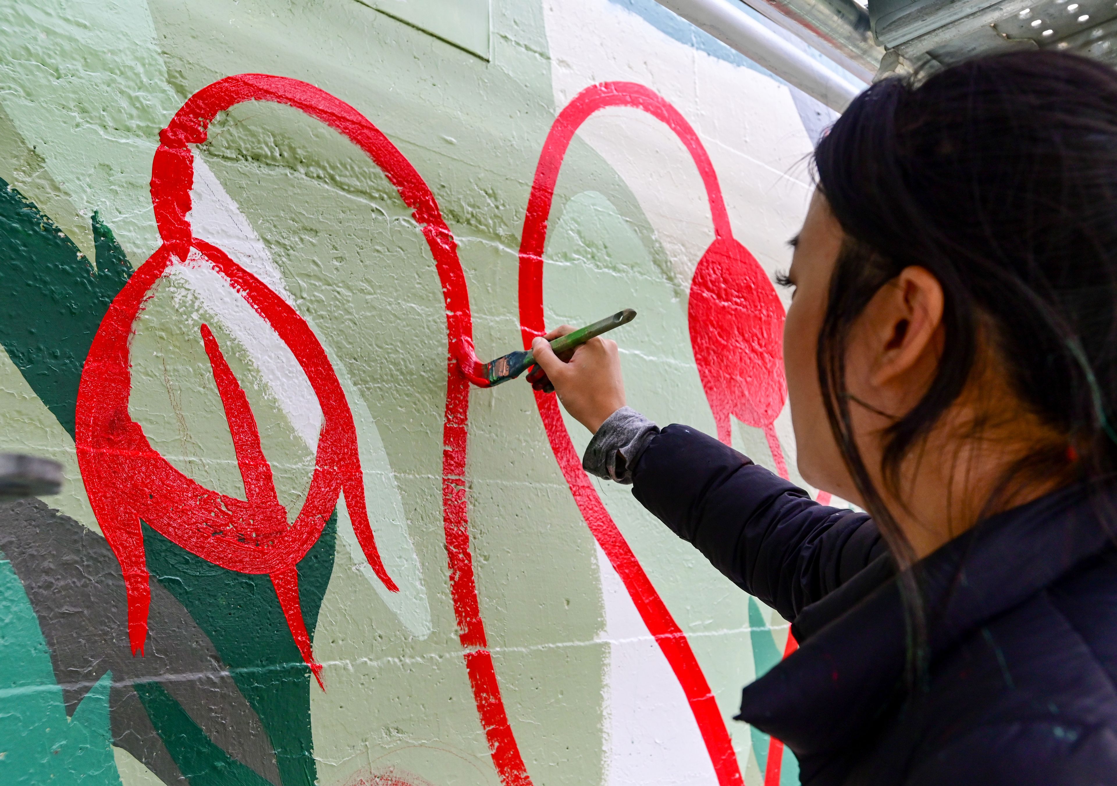 Tori Shao, an artist and landscape architect, works on a new mural in downtown Pullman.