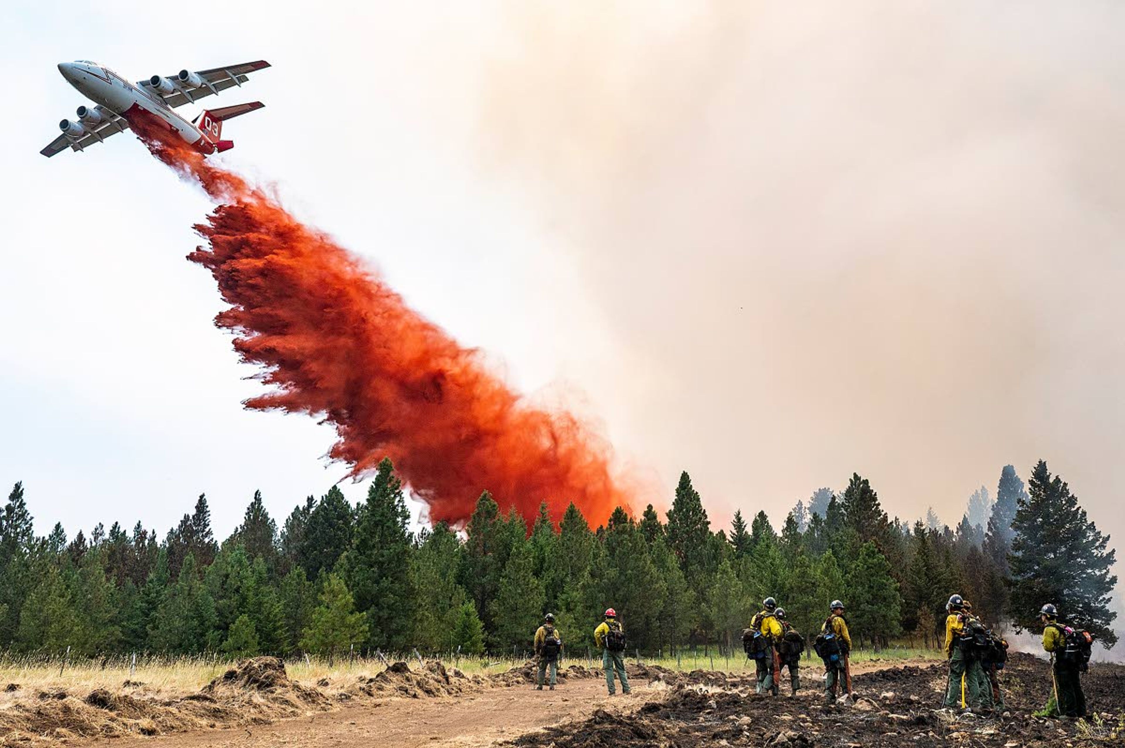 Wildland firefighters watch as a plane drops retardant on top of Harlow Ridge just east of where crews were building a fire line to keep the Lick Creek Fire in the gulch below on Monday afternoon off of Cloverland Road southwest of Asotin.